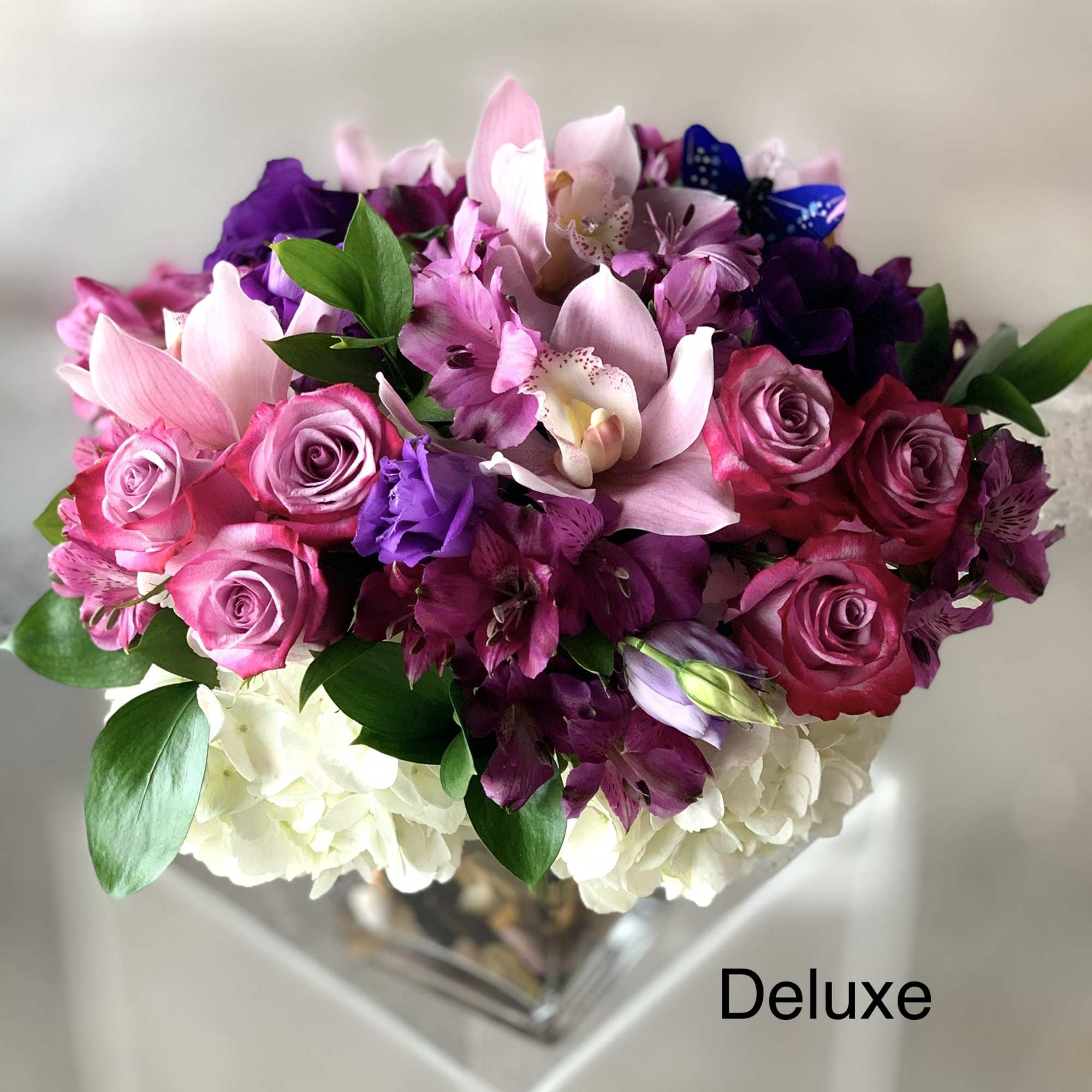 Pink and purple bouquet with roses, lilies, and white hydrangeas in a clear vase
