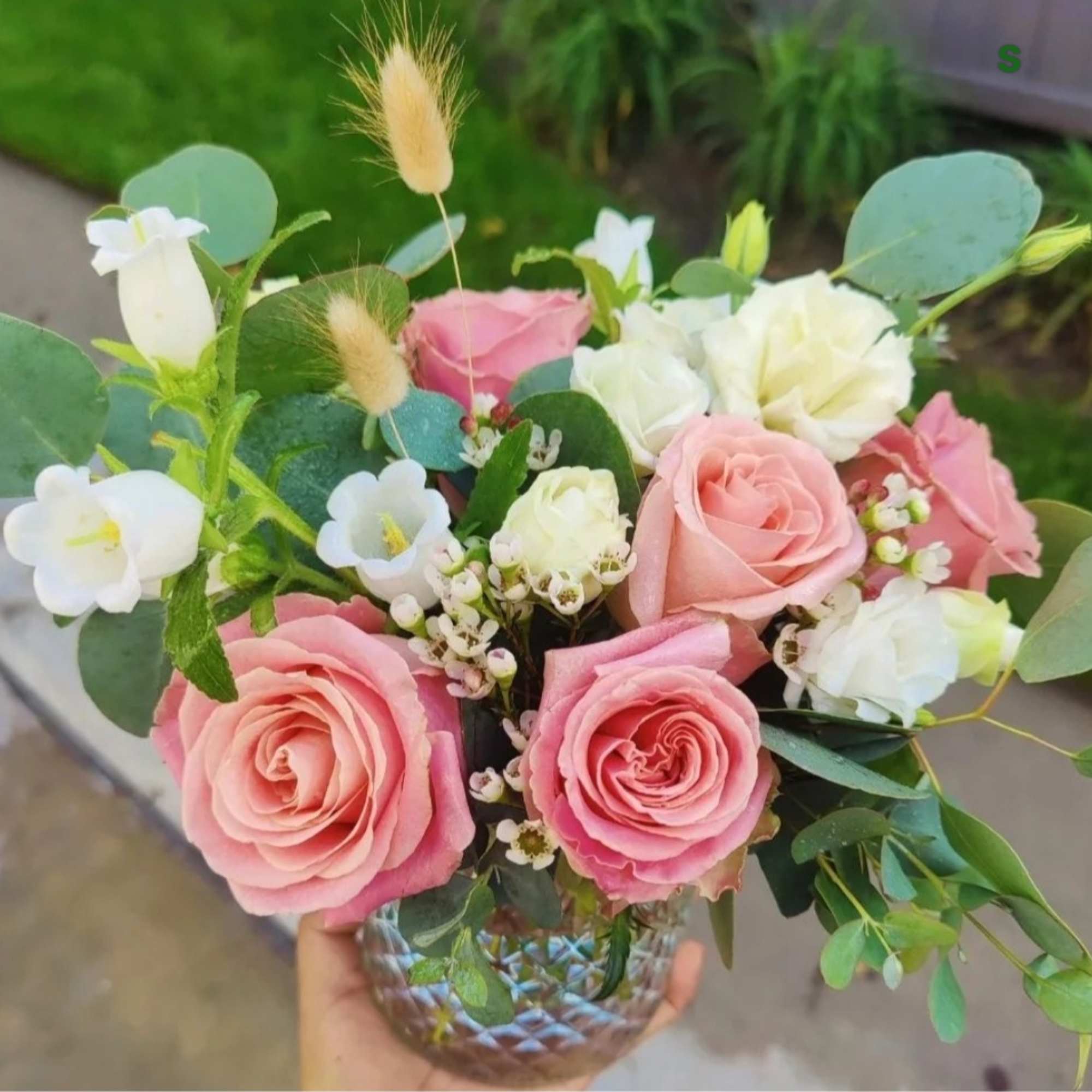 Pink and white rose bouquet in a glass vase with eucalyptus and small white blooms