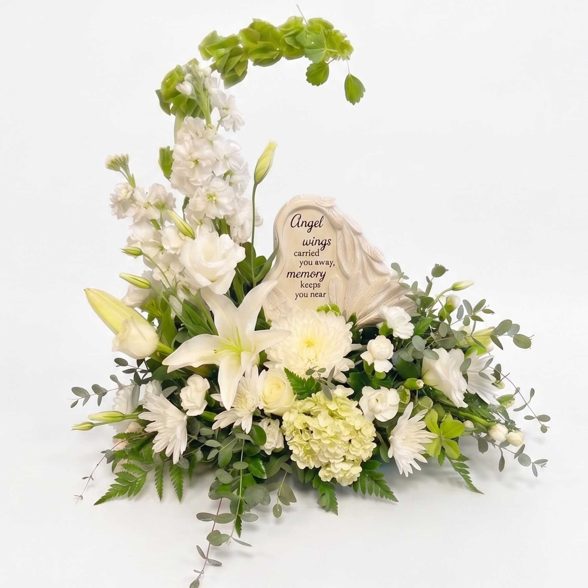 White sympathy floral arrangement with lilies and a memorial plaque