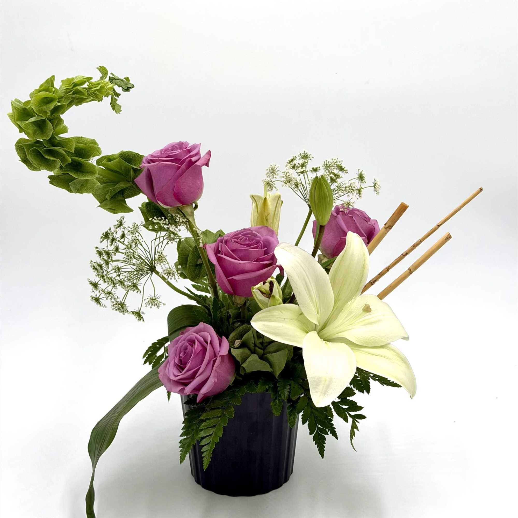 A graceful blend of lavender roses and elegant white lilies creates a