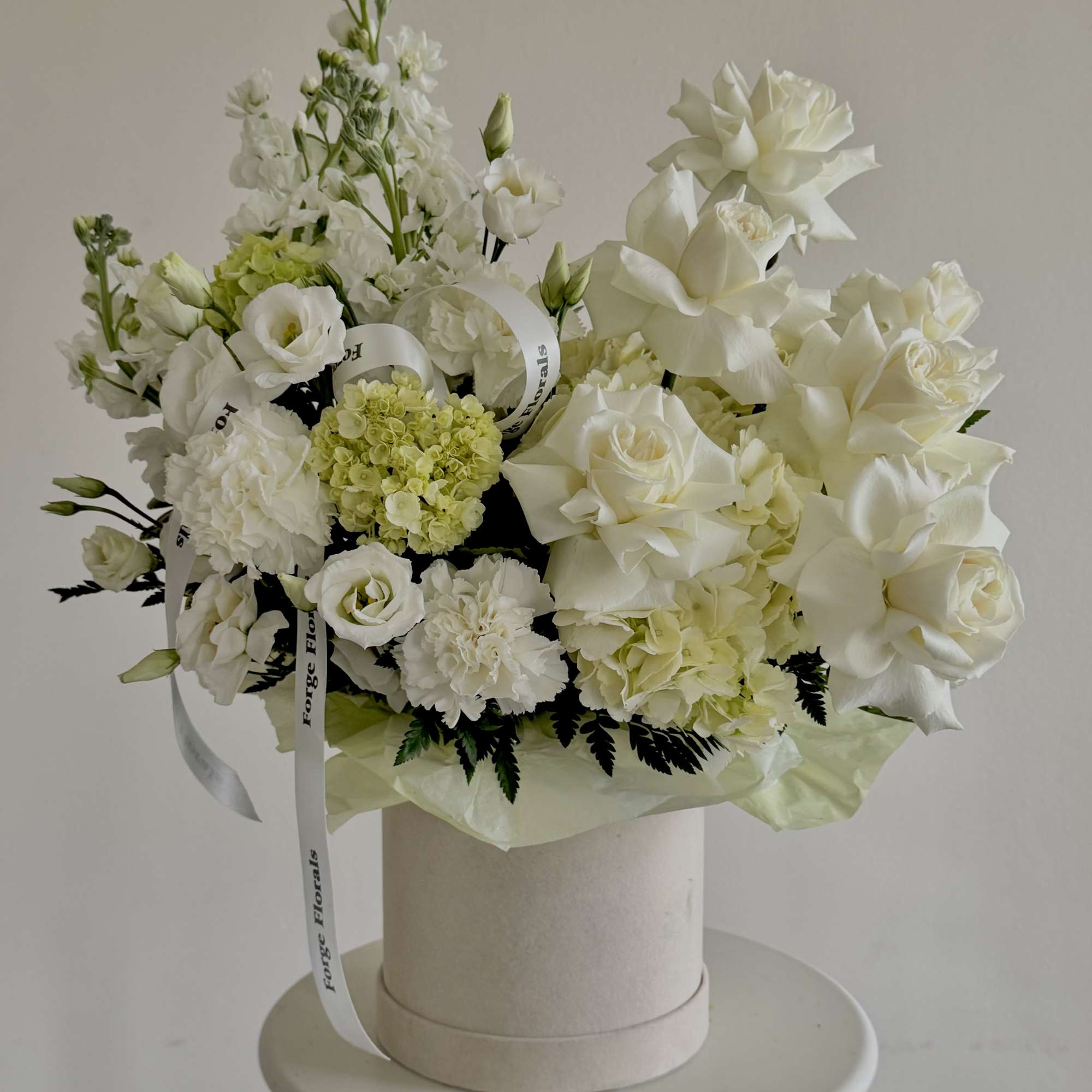 A soft, sculptural design in creamy whites and fresh greens. Layered roses