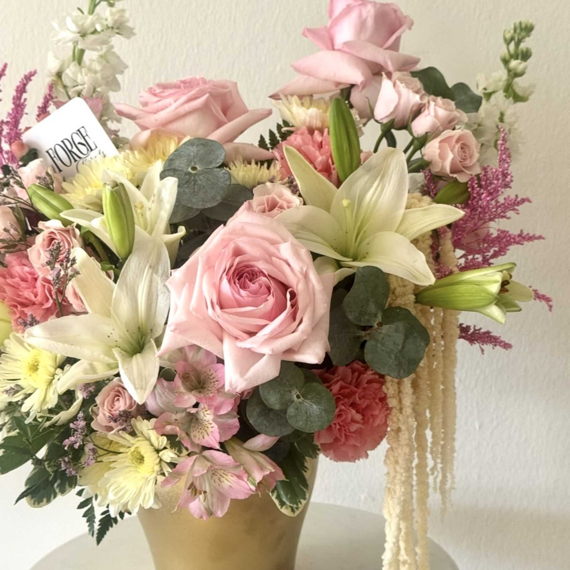 A lush garden-inspired arrangement featuring soft pink roses, delicate spray roses, elegant