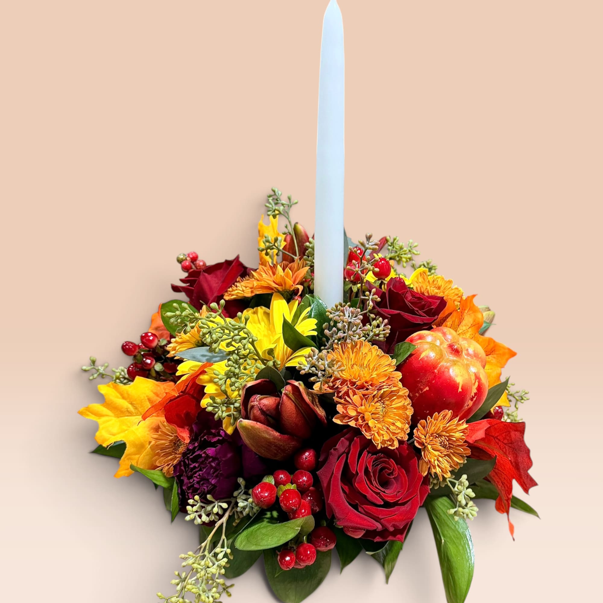 Autumn floral candle arrangement with red roses and a tall white taper candle
