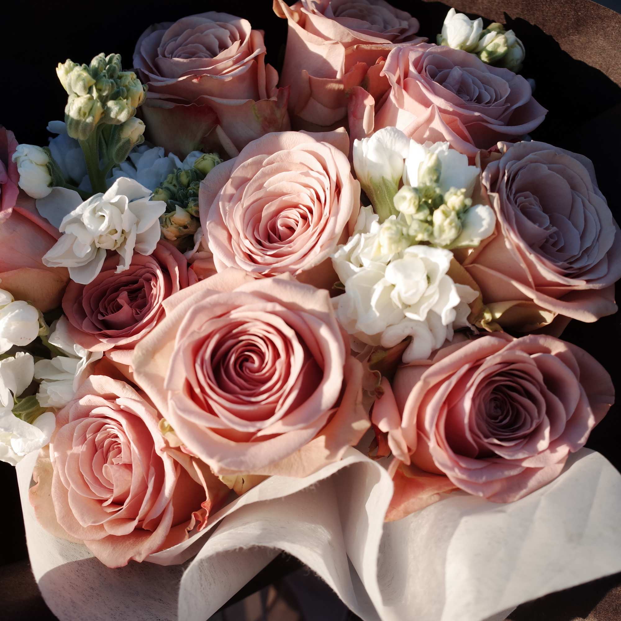 Bouquet of pale pink roses with small white flowers wrapped in paper