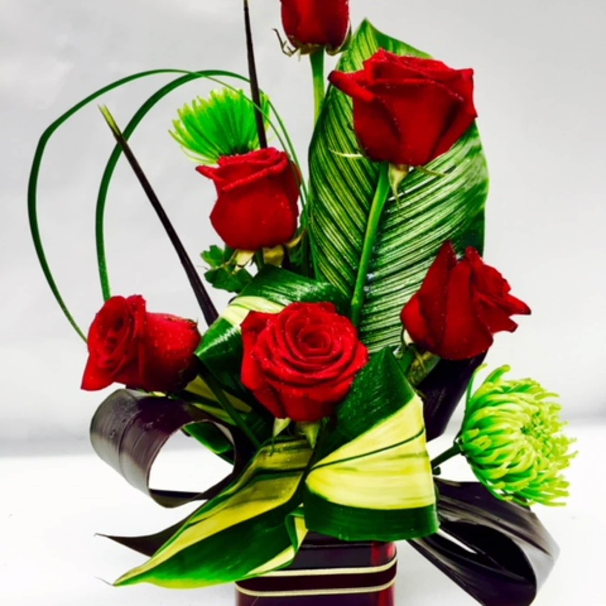 Red roses arranged with green decorative leaves in a vase