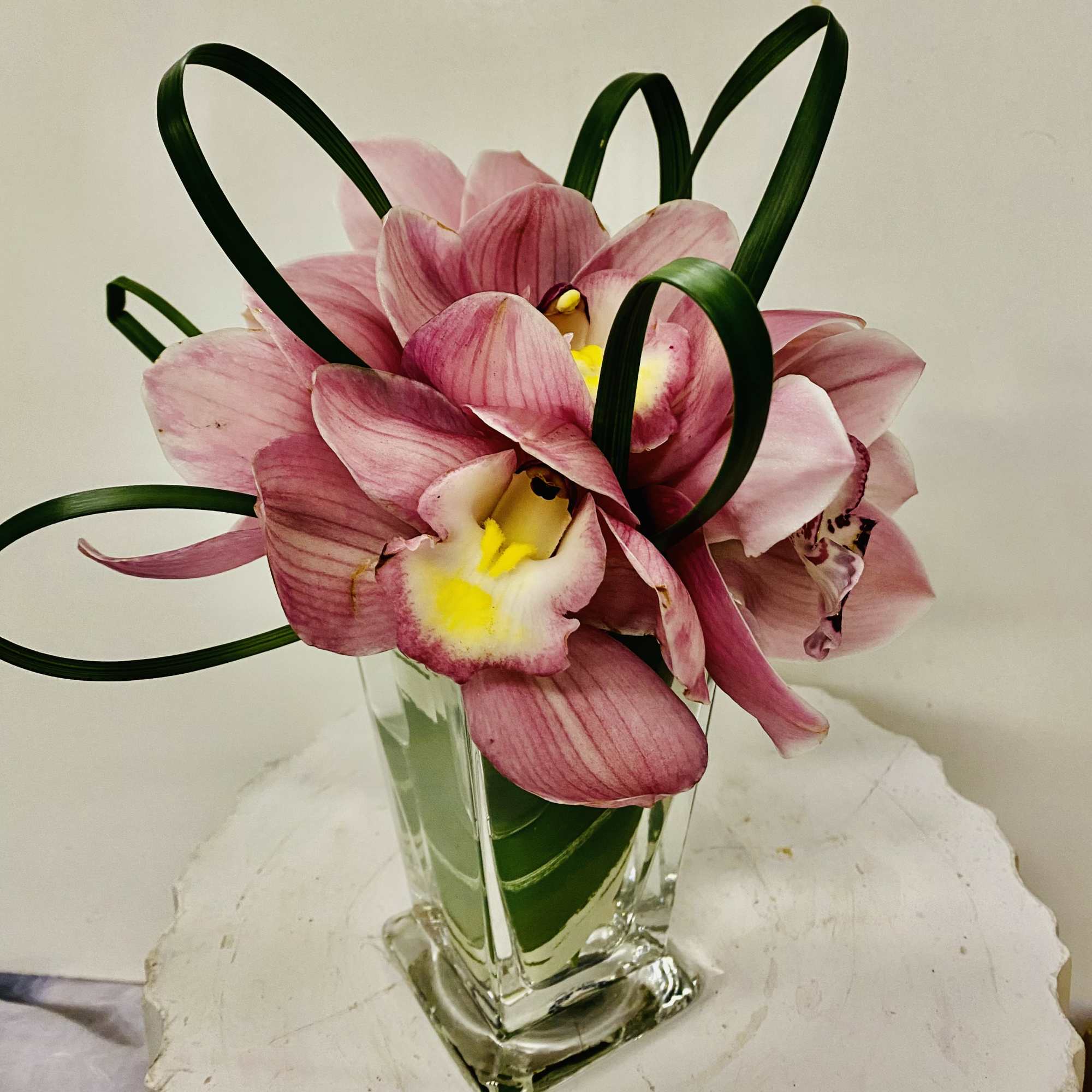 Pink orchid arrangement in a clear glass vase