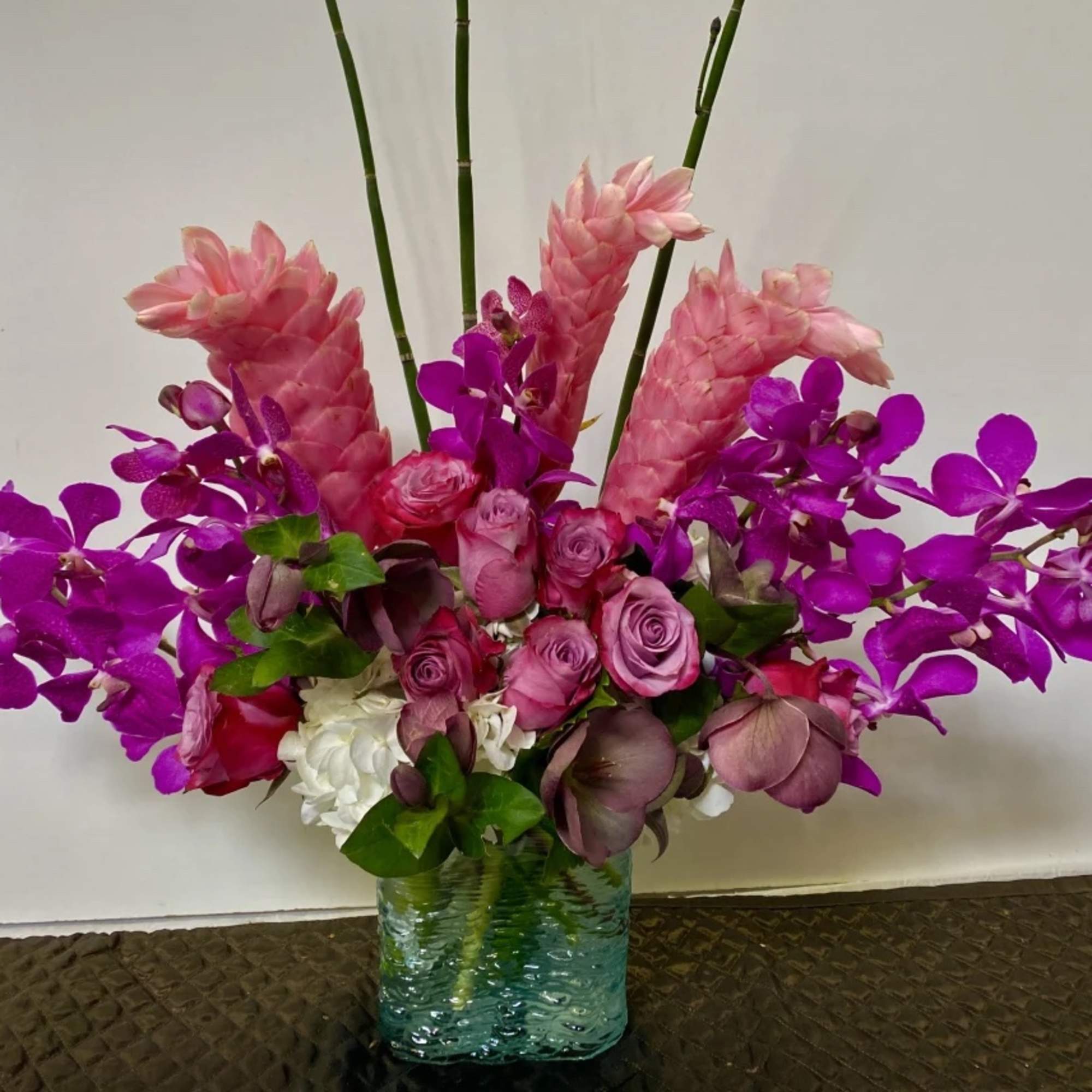 Pink and purple floral arrangement in a blue glass vase