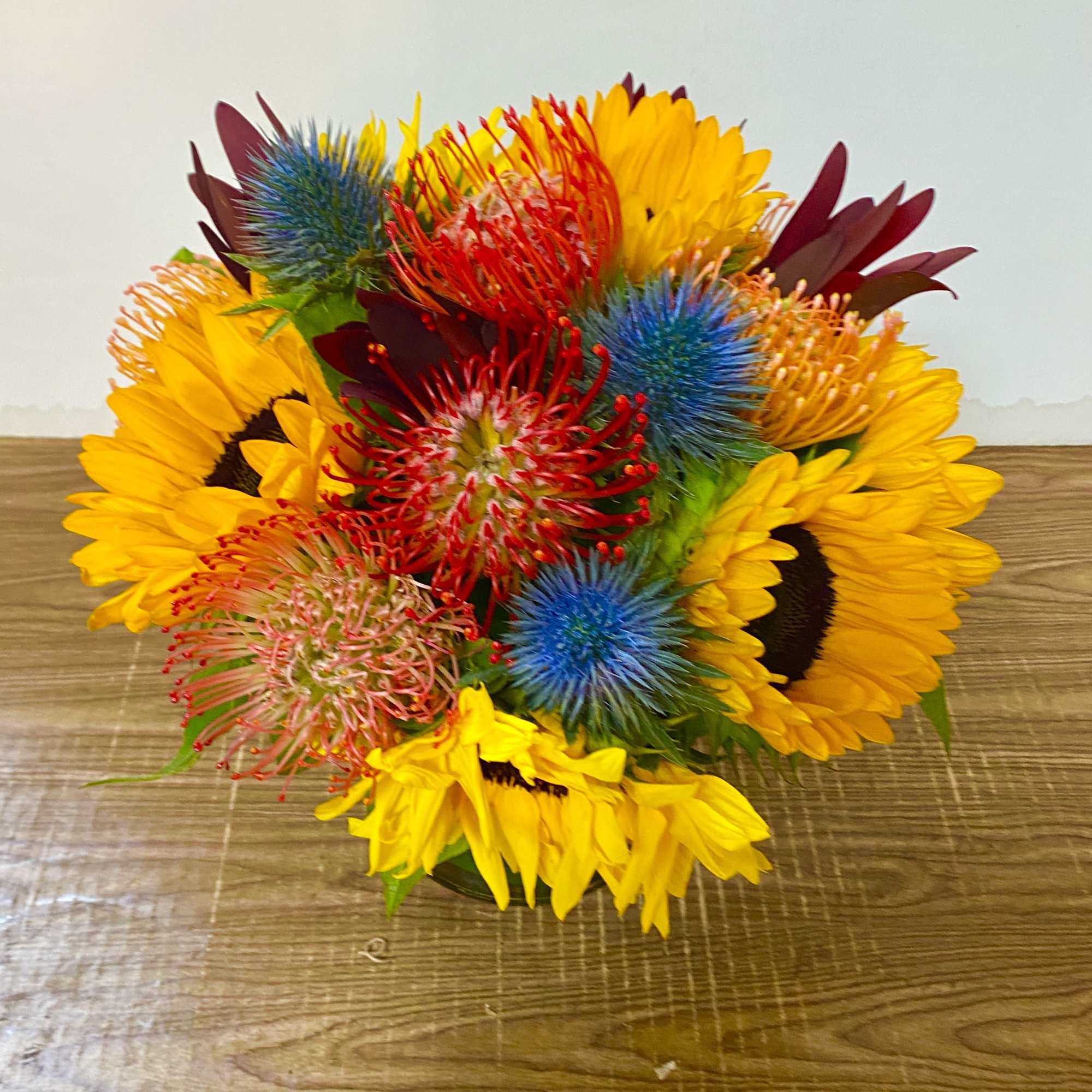 Bright mixed bouquet with sunflowers and spiky blue and red blooms