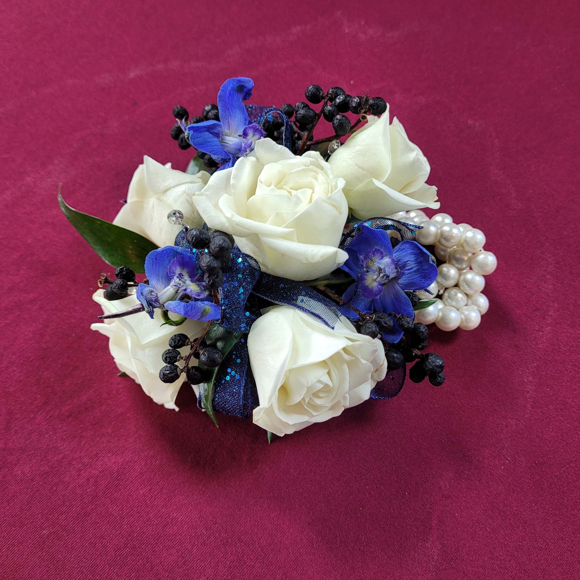 White roses with blue flowers and pearl accents on a pink background