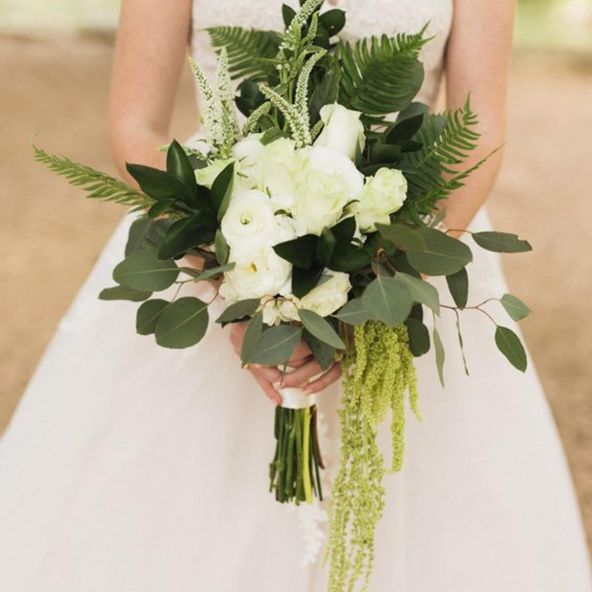 Bride holding a white and green bouquet with cascading greenery