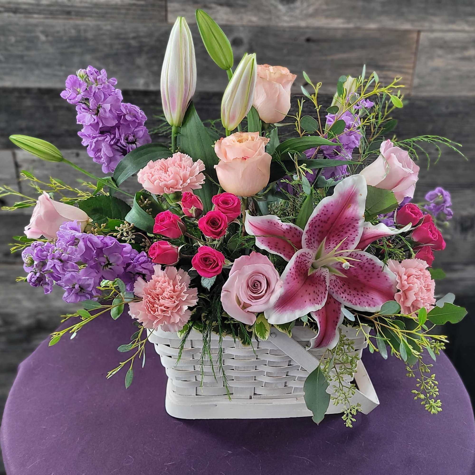 Mixed pink and purple flowers in a white basket