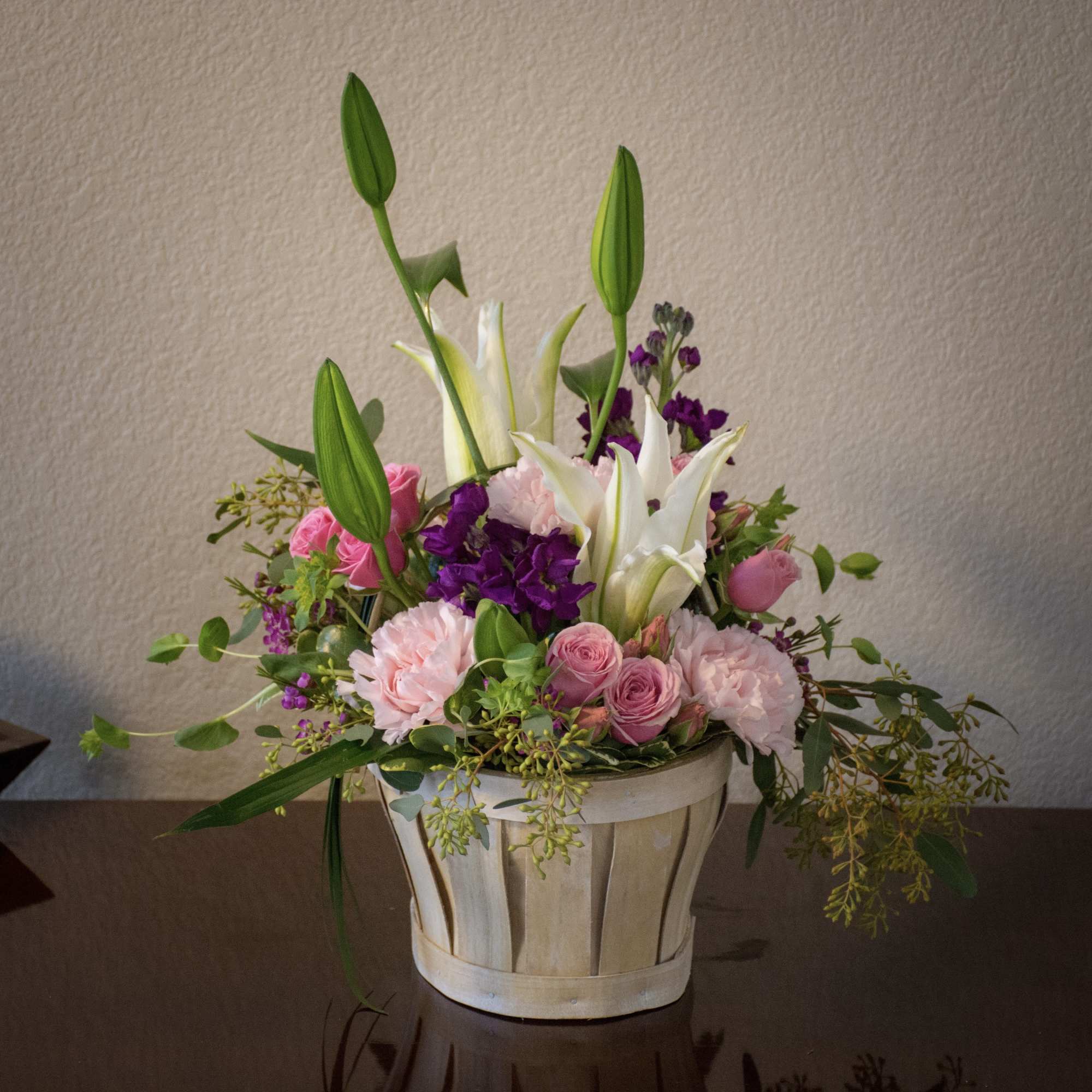 Pink and white floral arrangement in a basket with tall lily buds