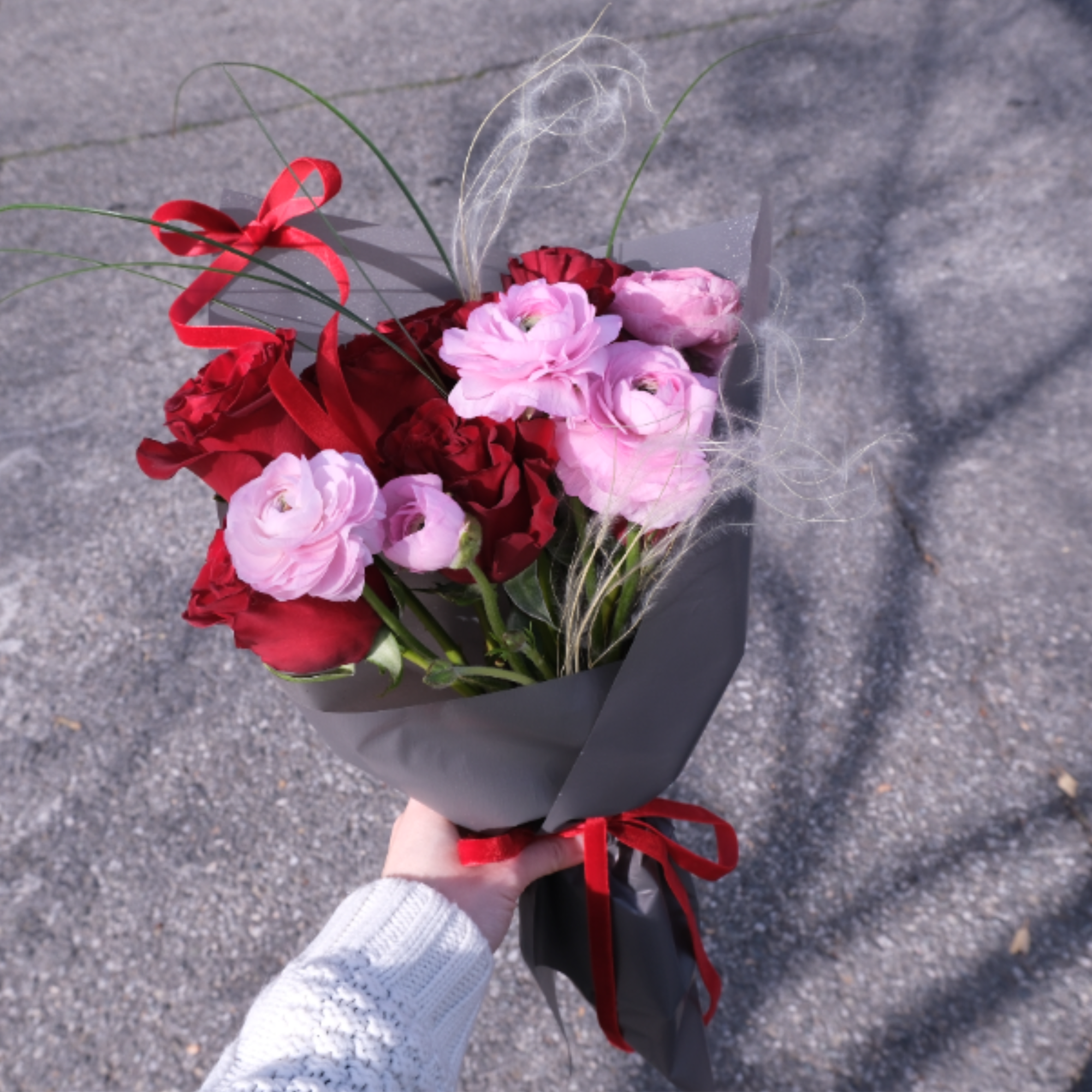 A dreamy, romantic bouquet where red roses meet pink ranunculus in a