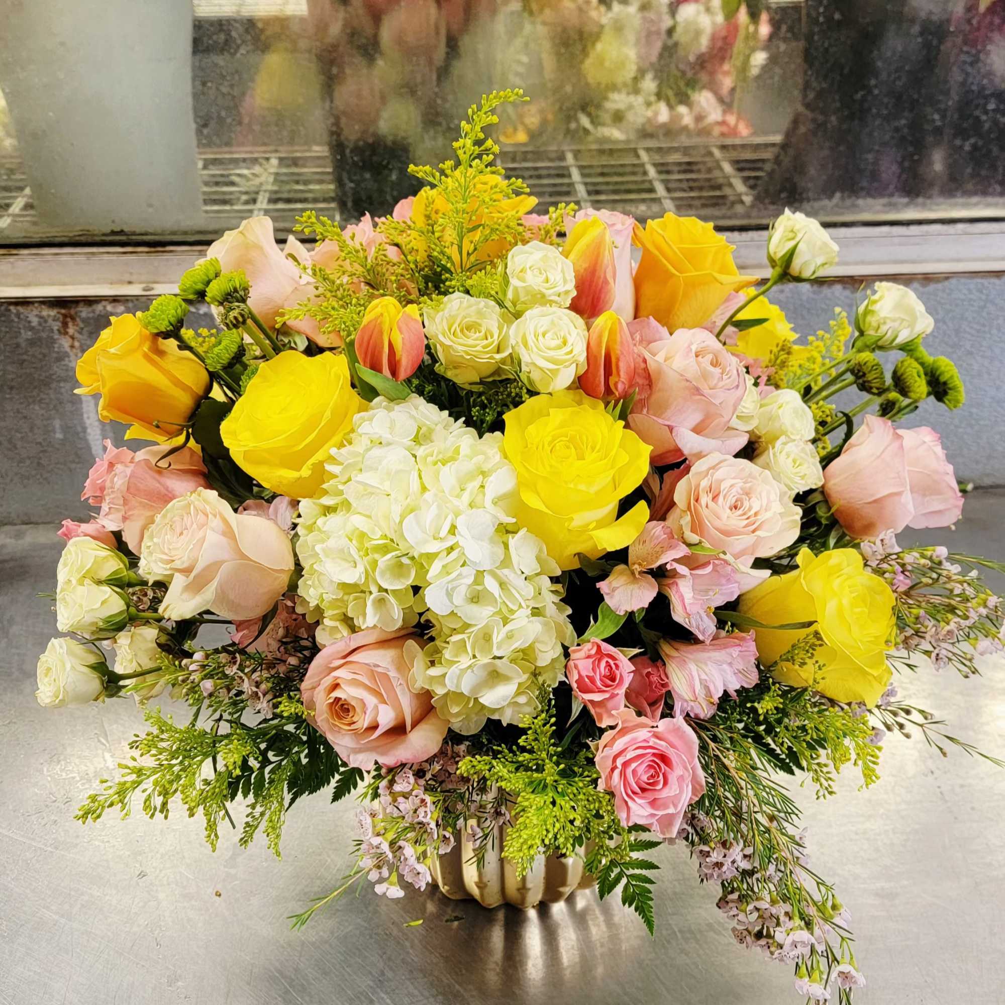 Mixed bouquet of yellow and pink roses with white hydrangea in a vase