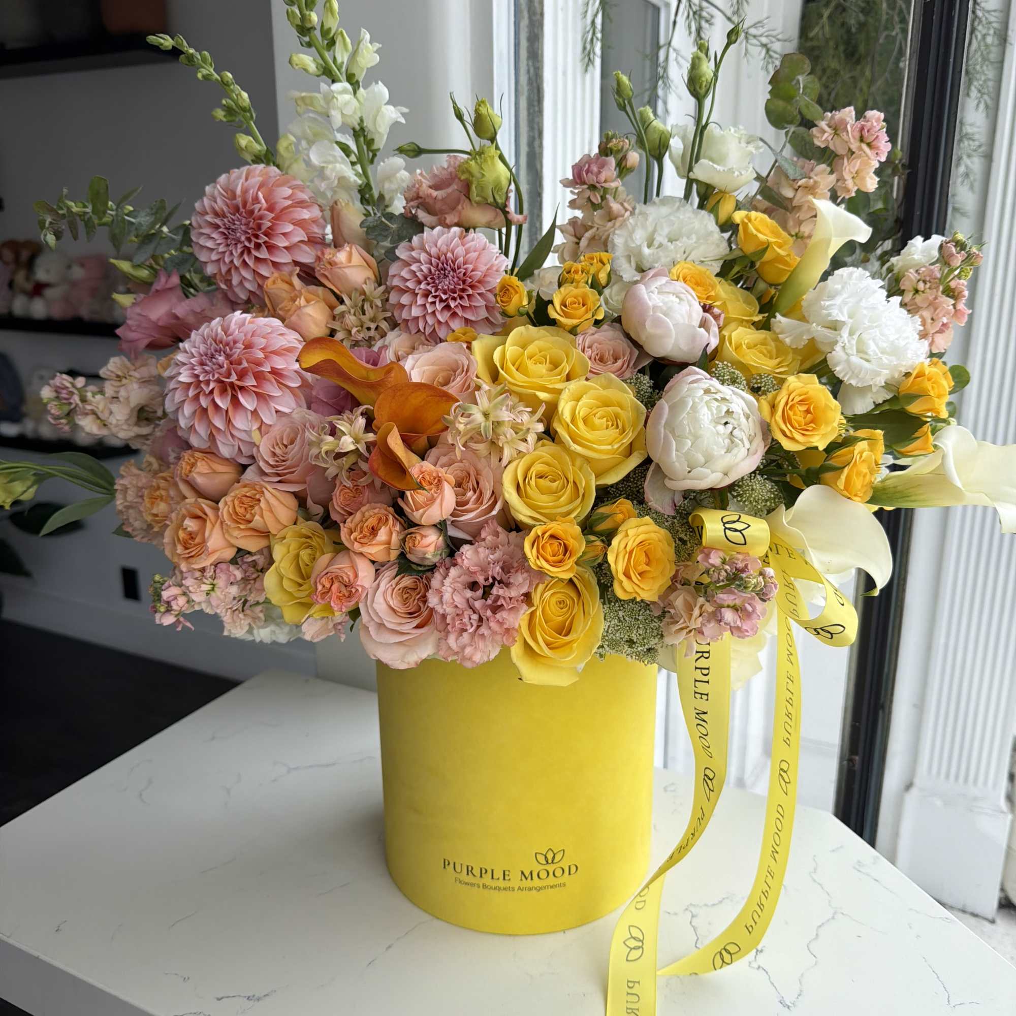 Large mixed bouquet in a yellow hatbox with pink, white, and yellow flowers