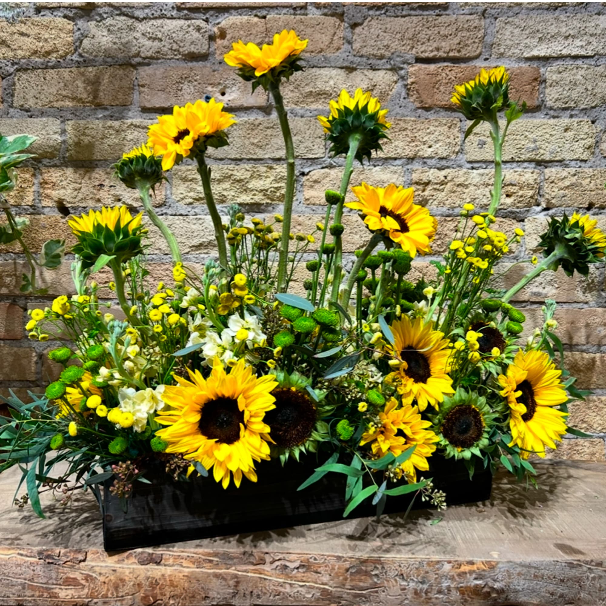 Sunflower arrangement in a black rectangular container with mixed yellow blooms