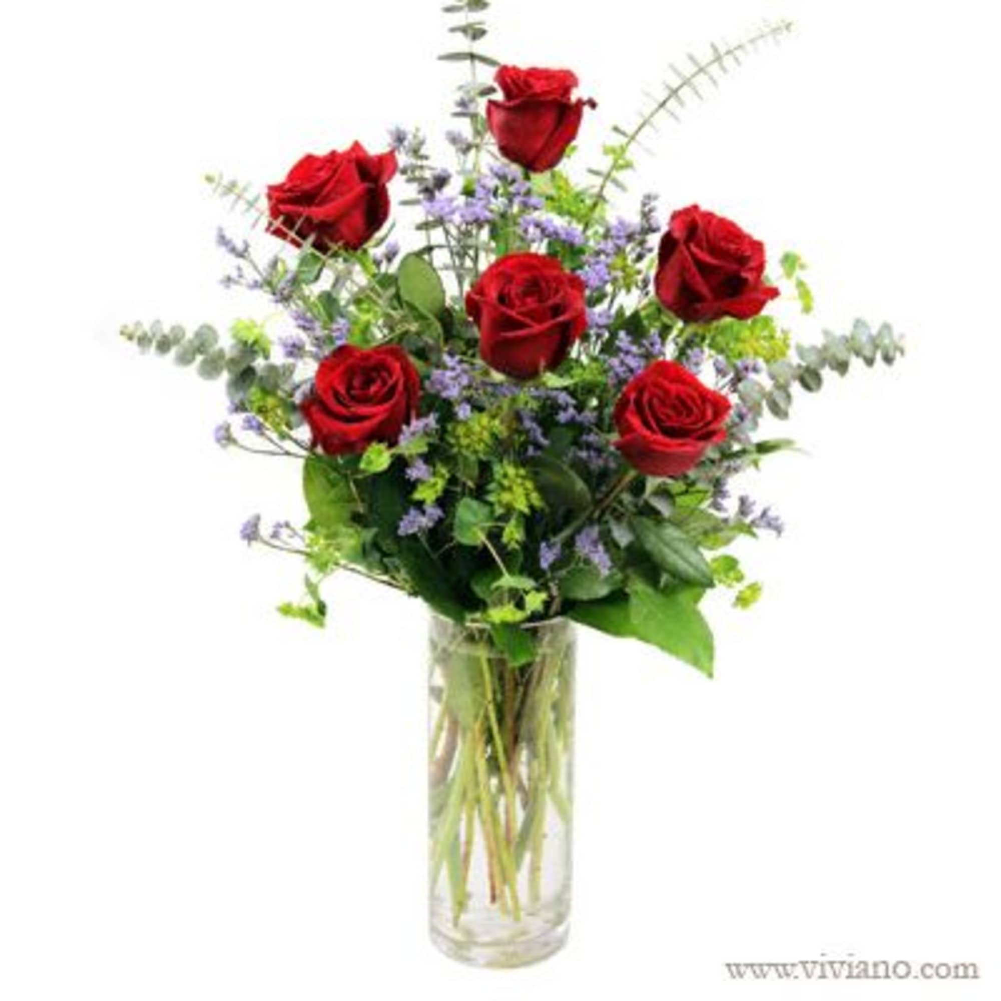 Red roses and purple filler flowers in a clear glass vase