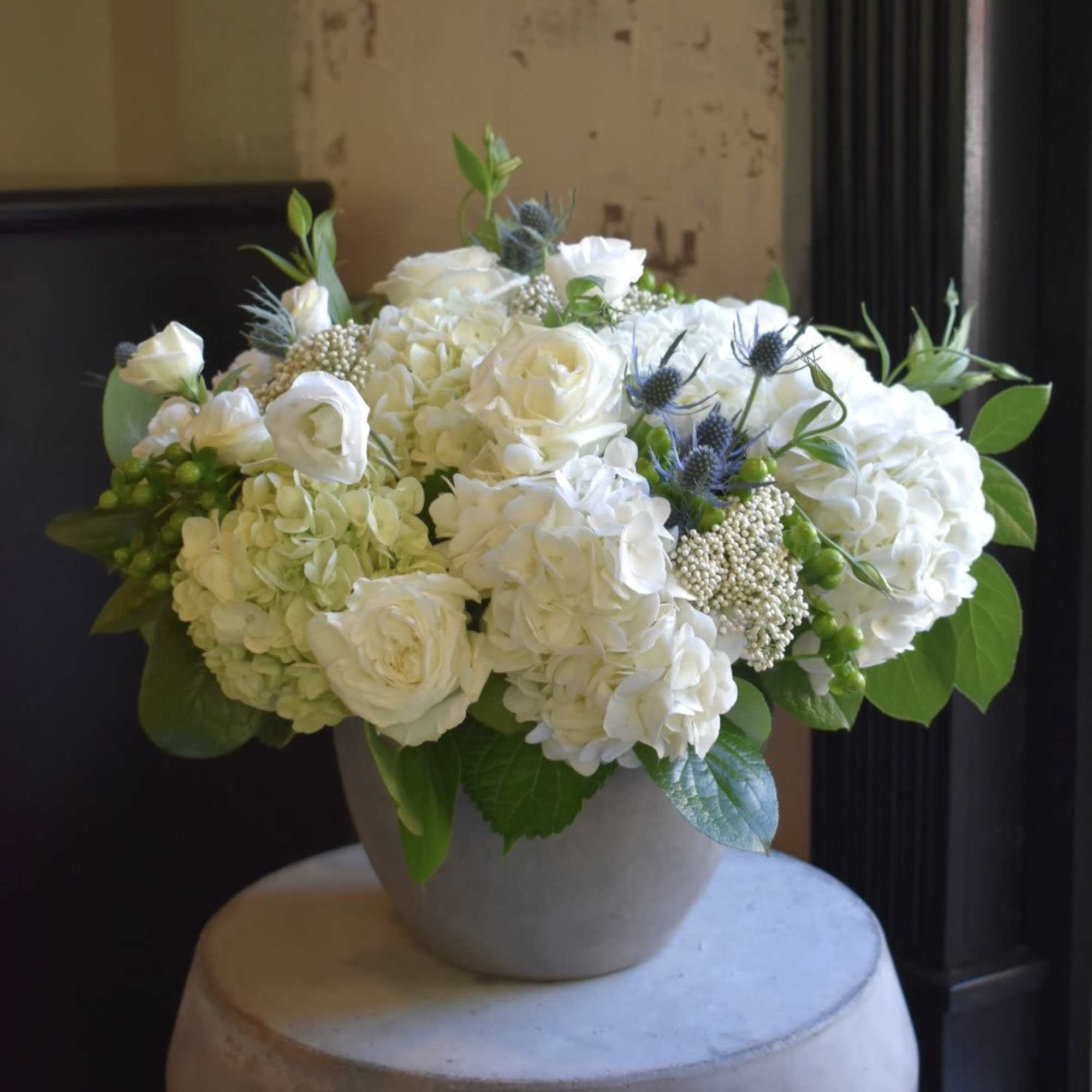 White floral arrangement in a round vase with green accents