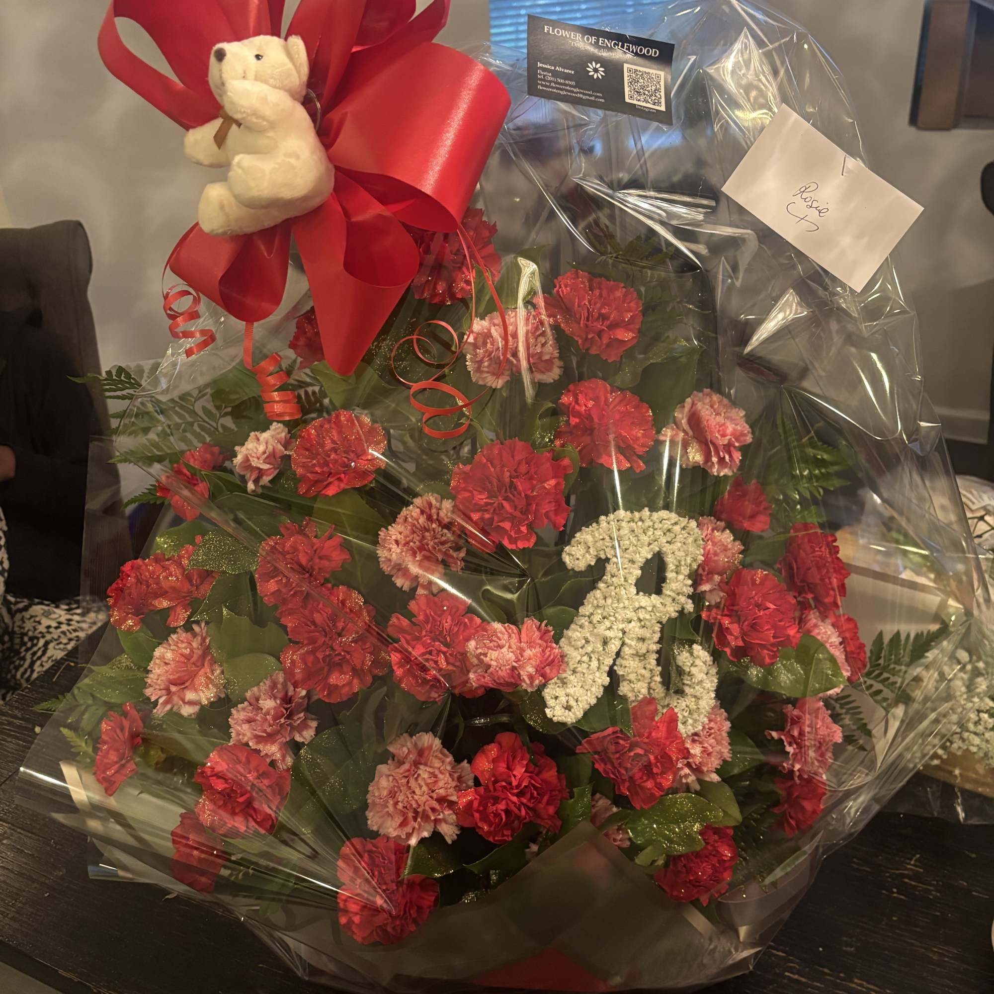 Wrapped bouquet of red and pink carnations with a teddy bear topper