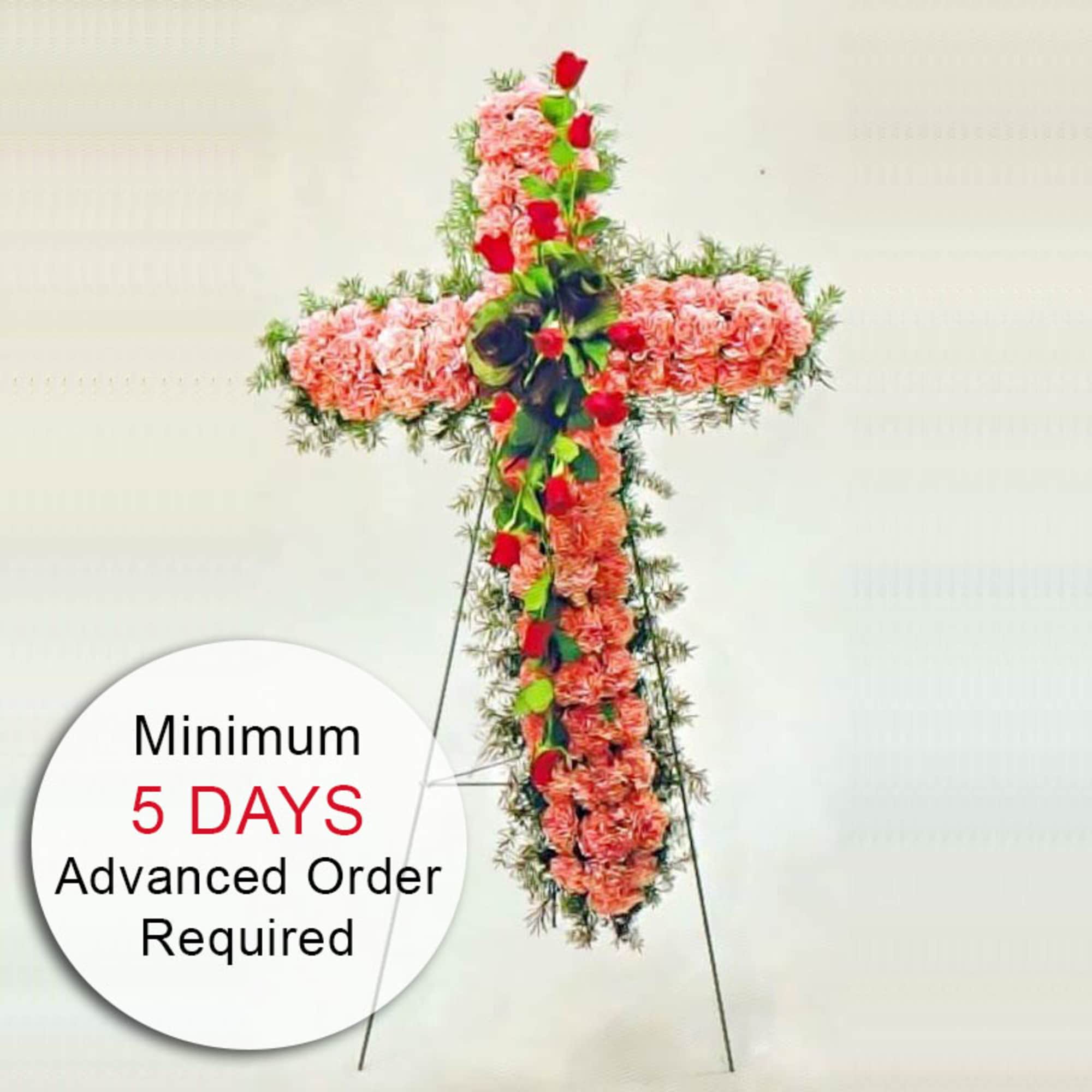 Tall floral cross of pink blooms with red roses on a metal easel stand