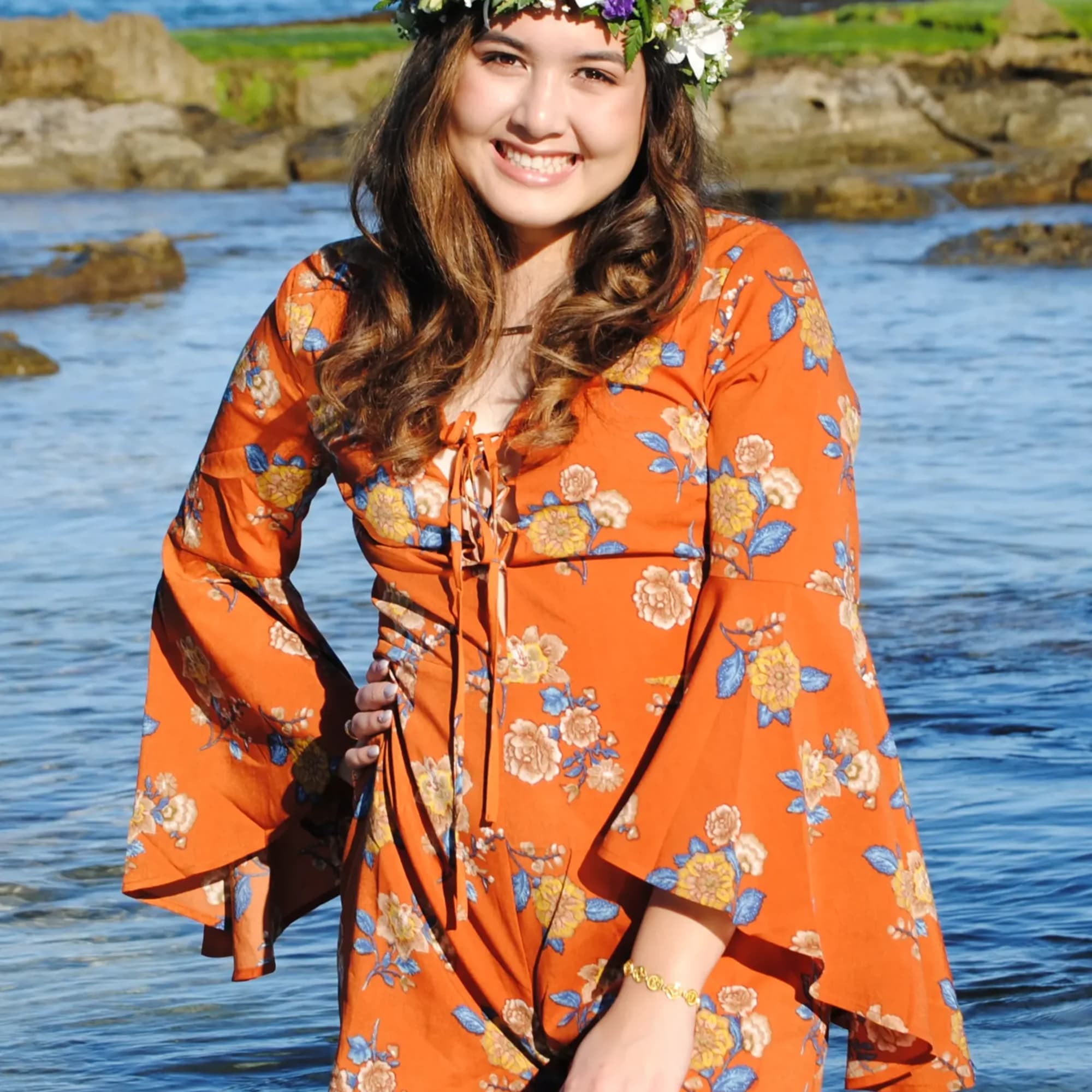 Young woman wearing a colorful flower crown standing by the ocean