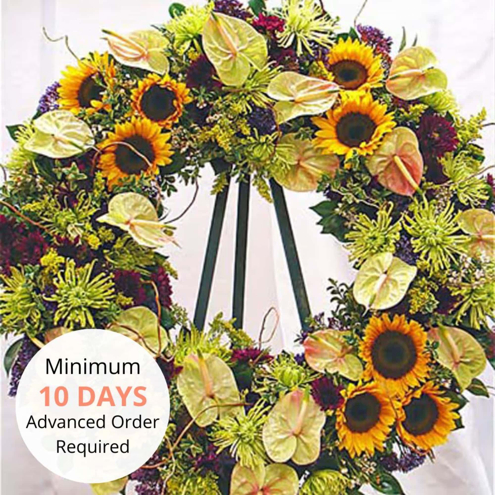 Large standing wreath with yellow sunflowers and mixed blooms on a tripod stand