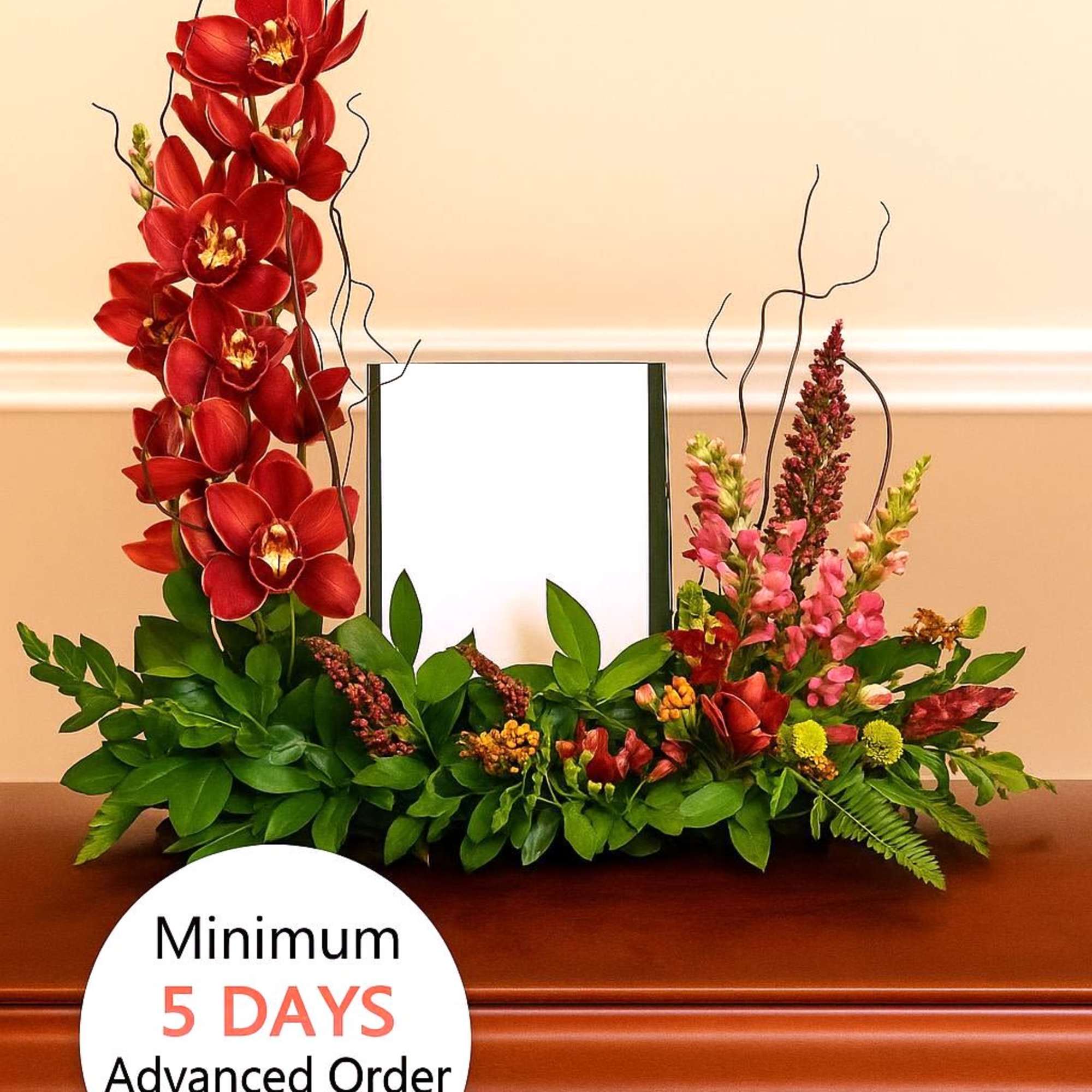 Red orchid and pink flower memorial arrangement framing a photo on a wooden casket