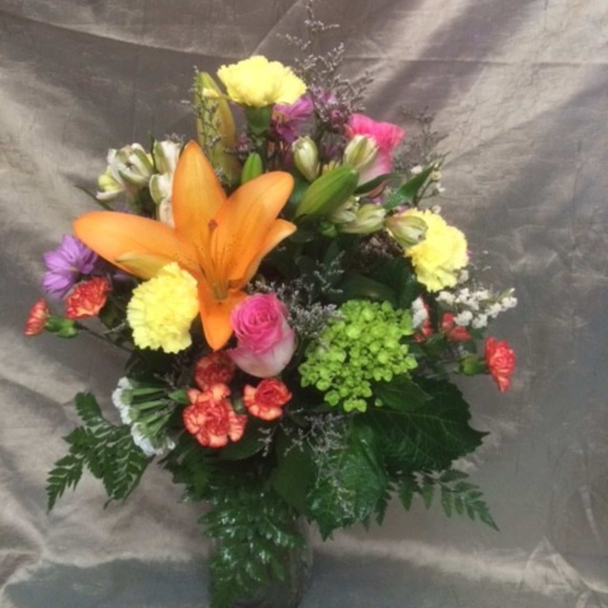 Colorful mixed bouquet with an orange lily in a glass vase