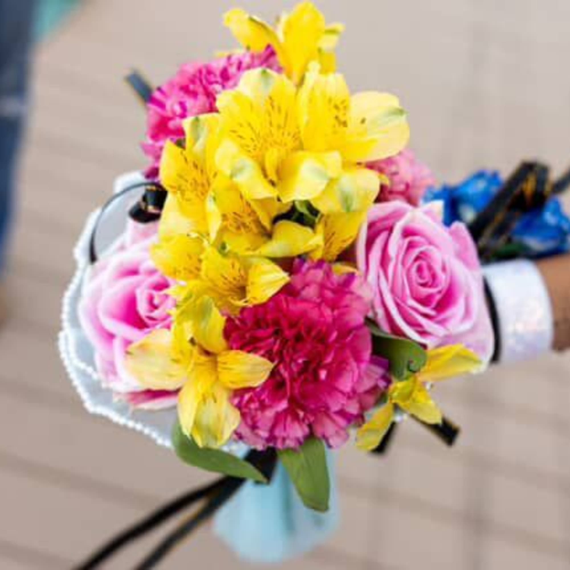 Handheld bouquet of pink roses, yellow alstroemeria, and magenta flowers