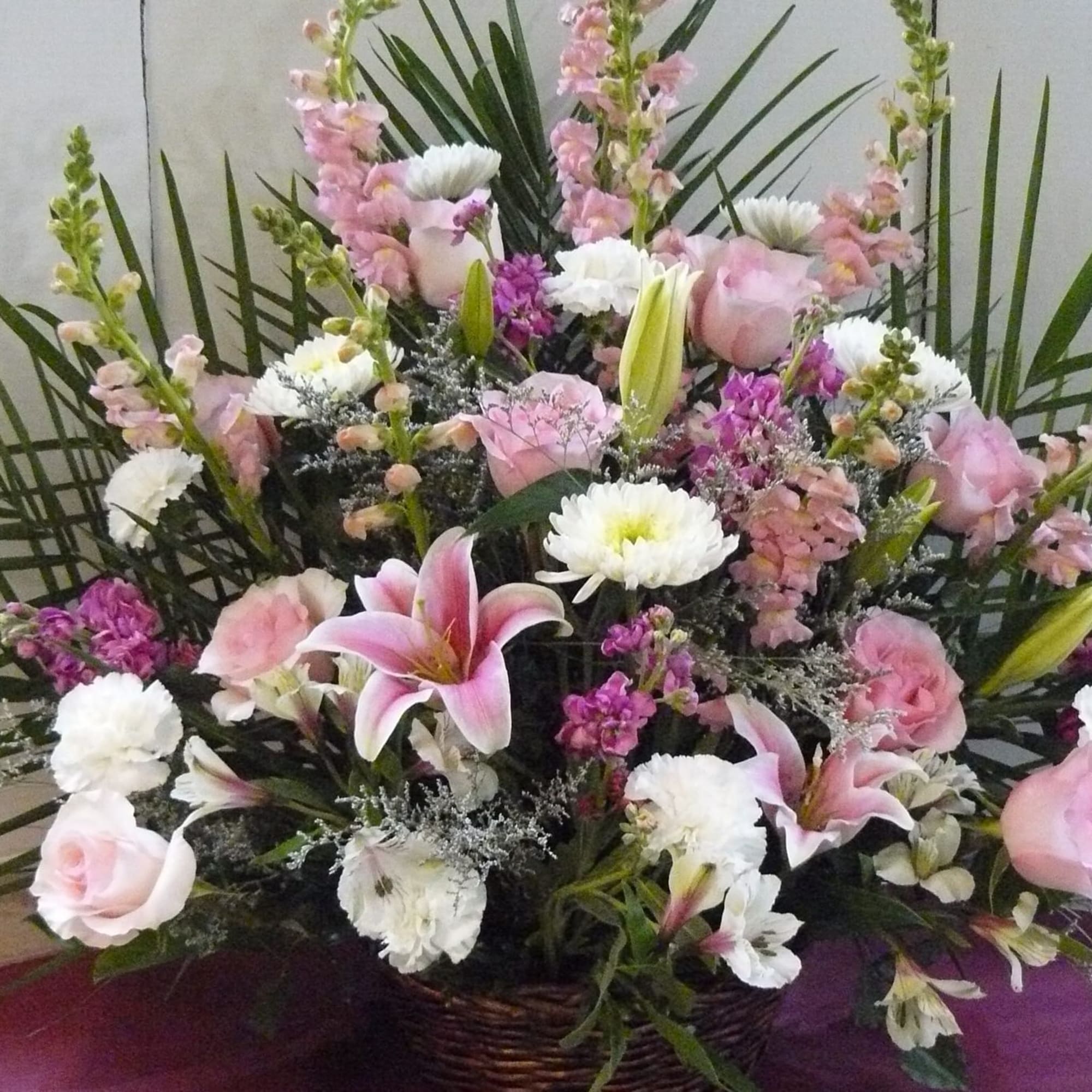 Pink and white floral arrangement with lilies, roses, and carnations in a basket