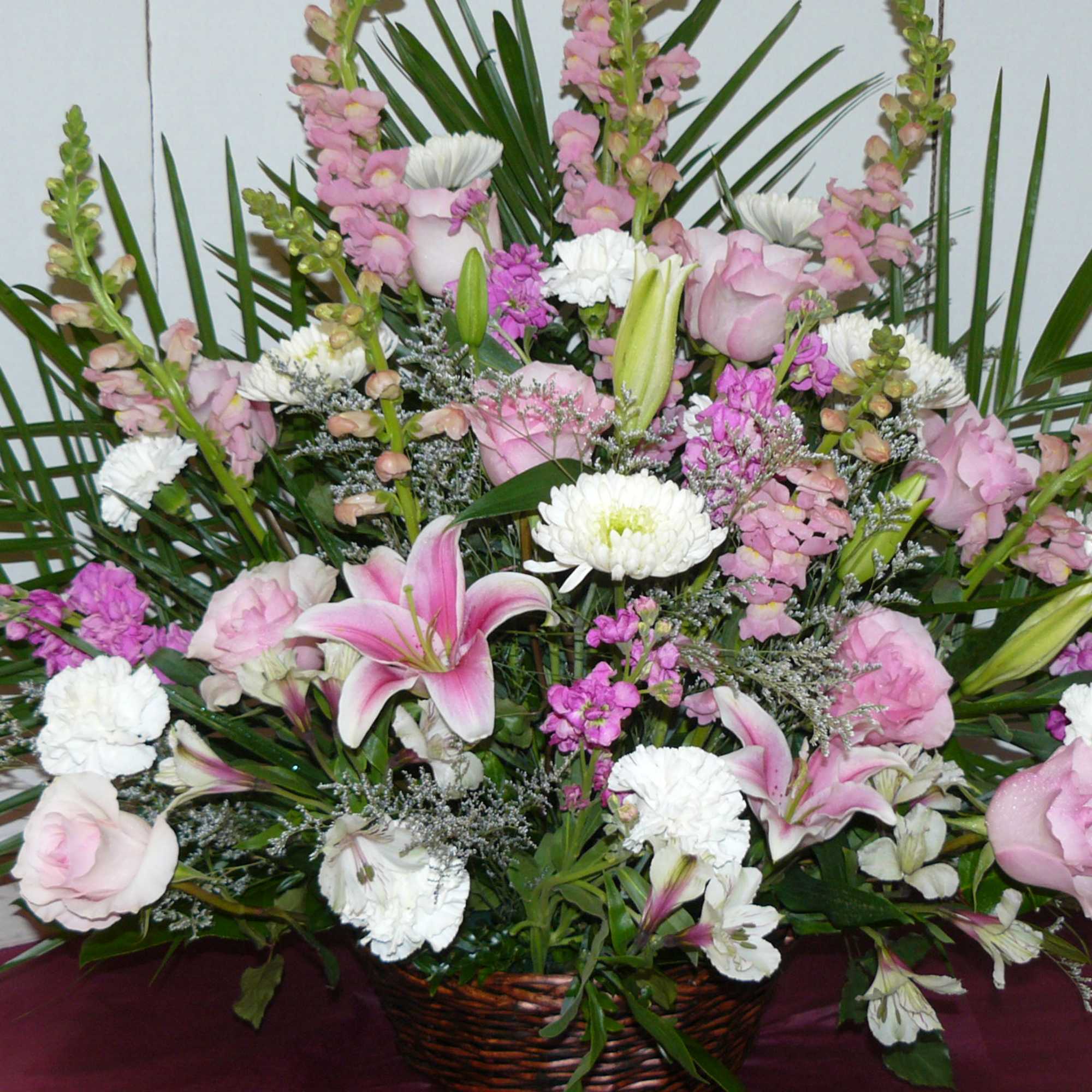 Large basket arrangement of pink and white flowers with palm fronds
