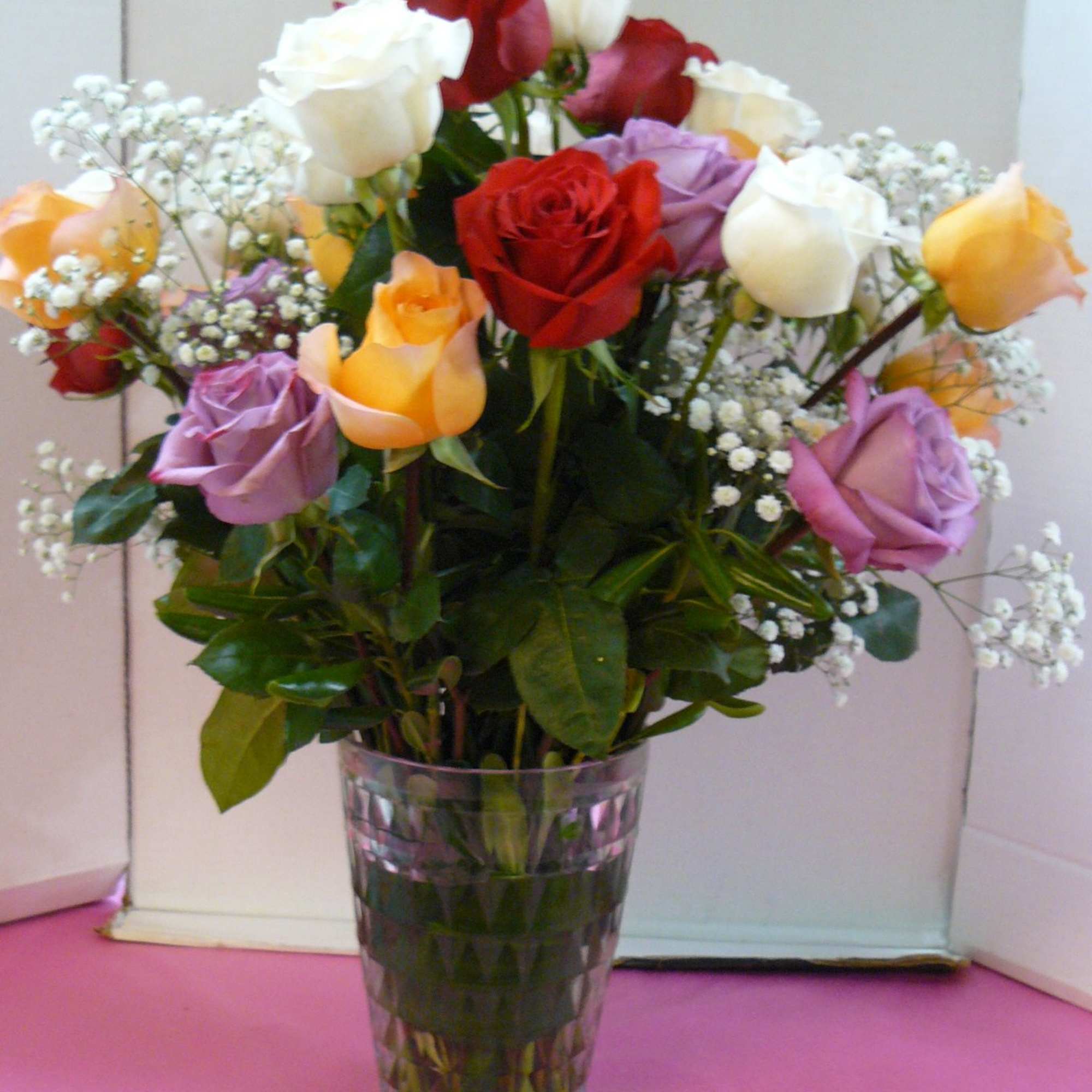 Mixed roses in a clear glass vase with baby's breath