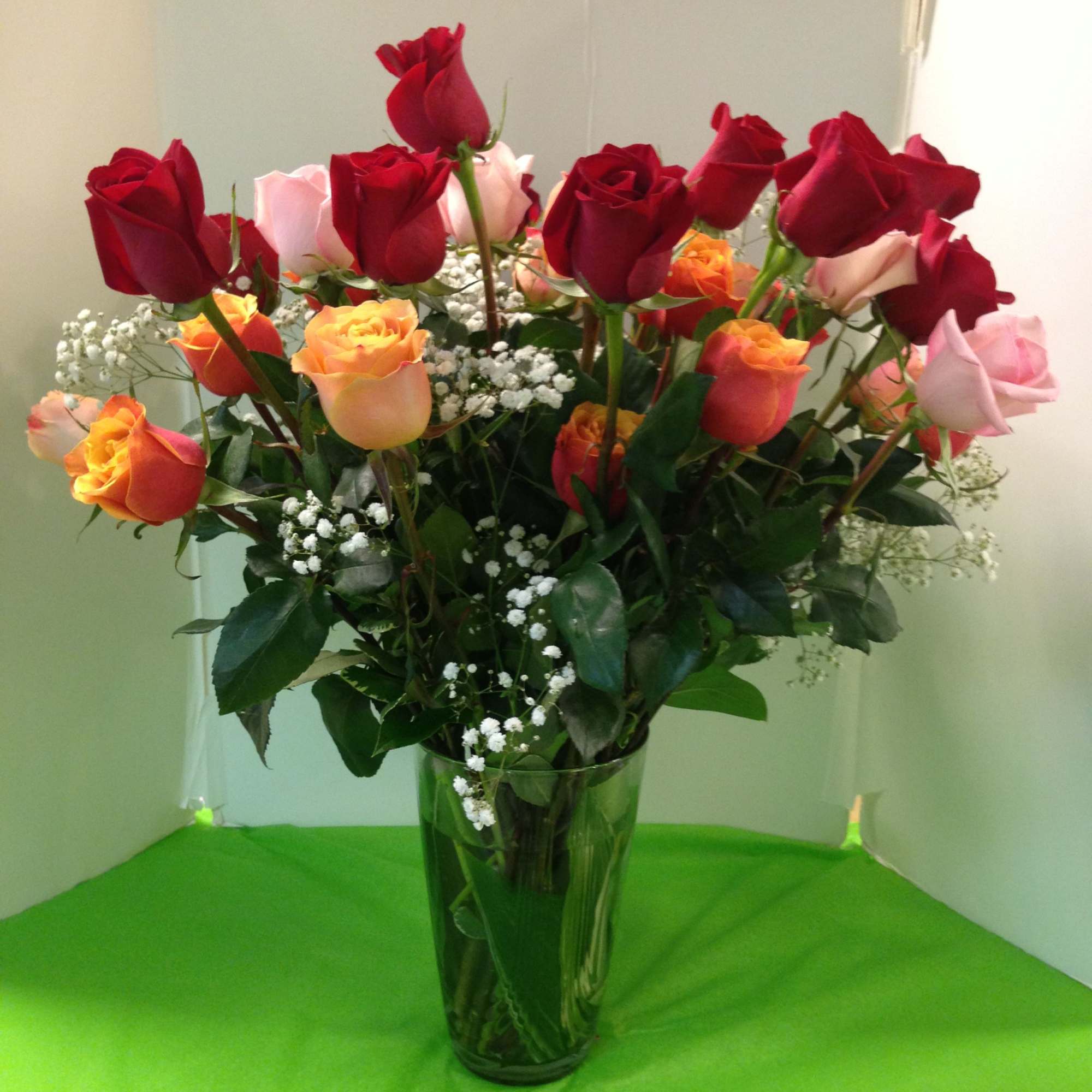 Bouquet of red, pink, and orange roses in a clear glass vase