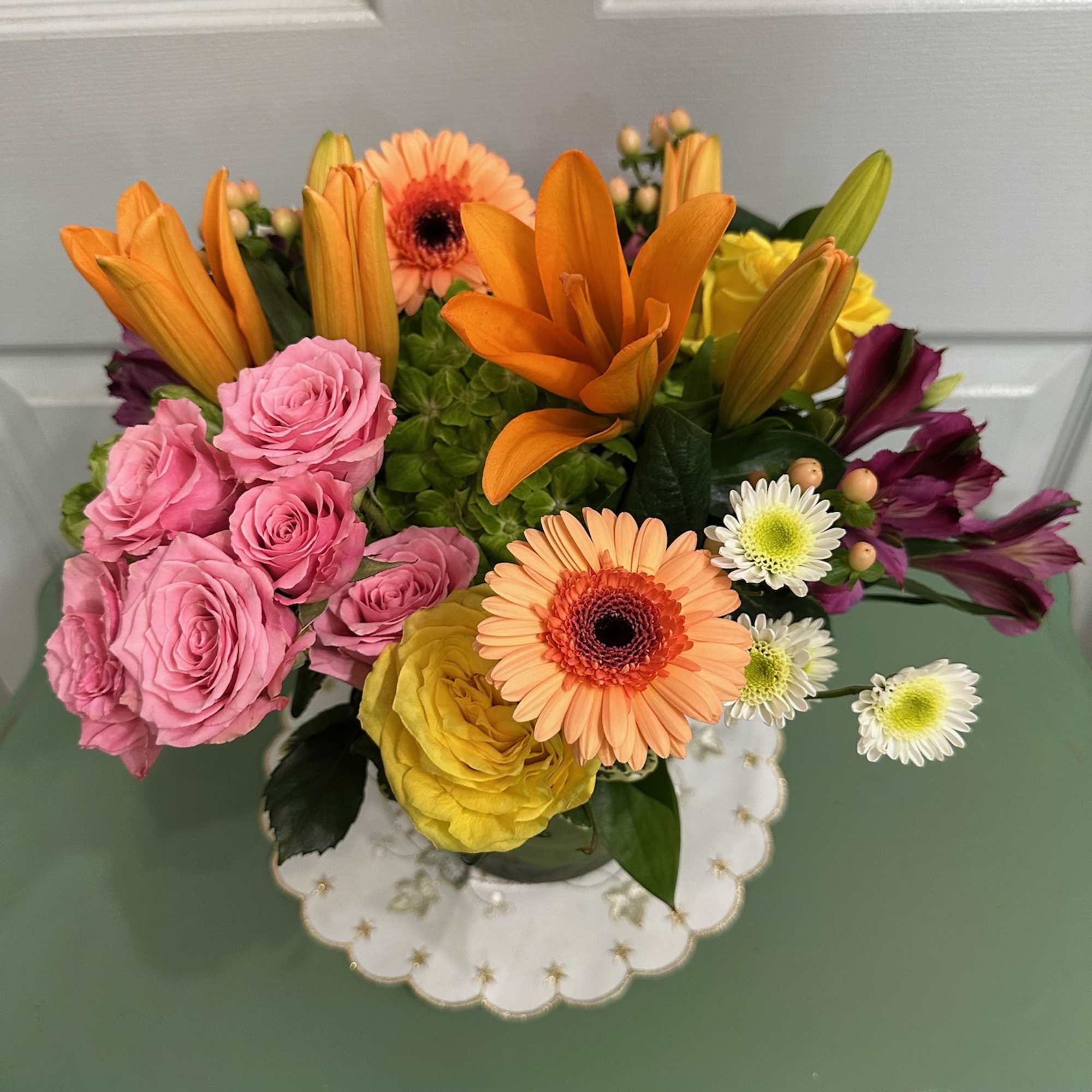 Mixed bouquet with pink roses, orange lilies, and gerbera daisies in a vase