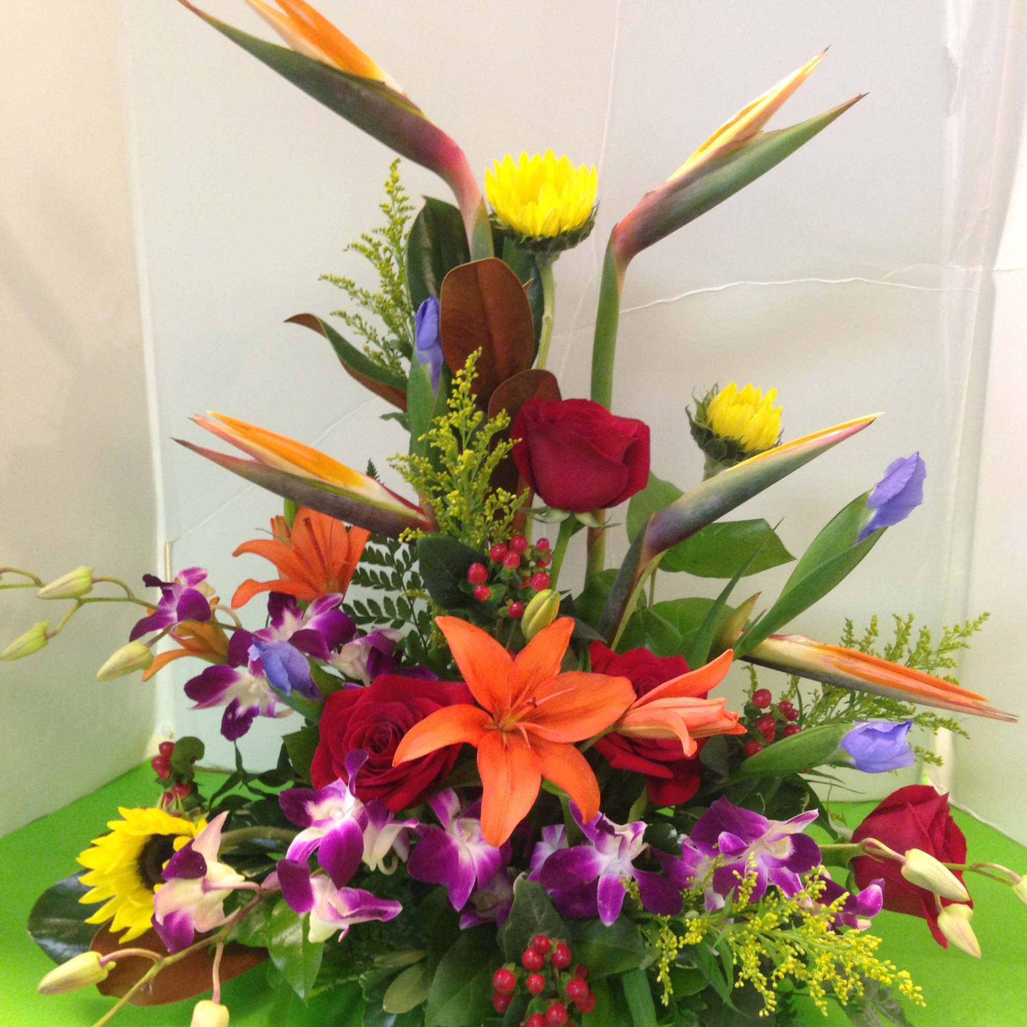 Tropical bouquet with orange birds of paradise, red roses, and purple orchids
