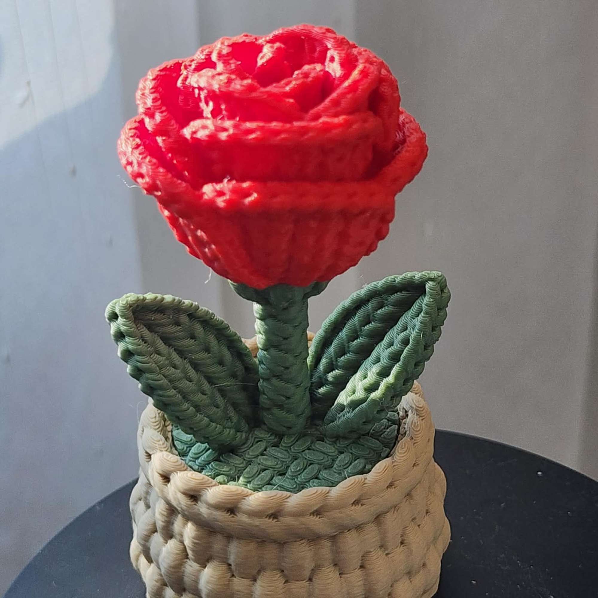 Red rose-shaped decorative piece in a woven basket planter