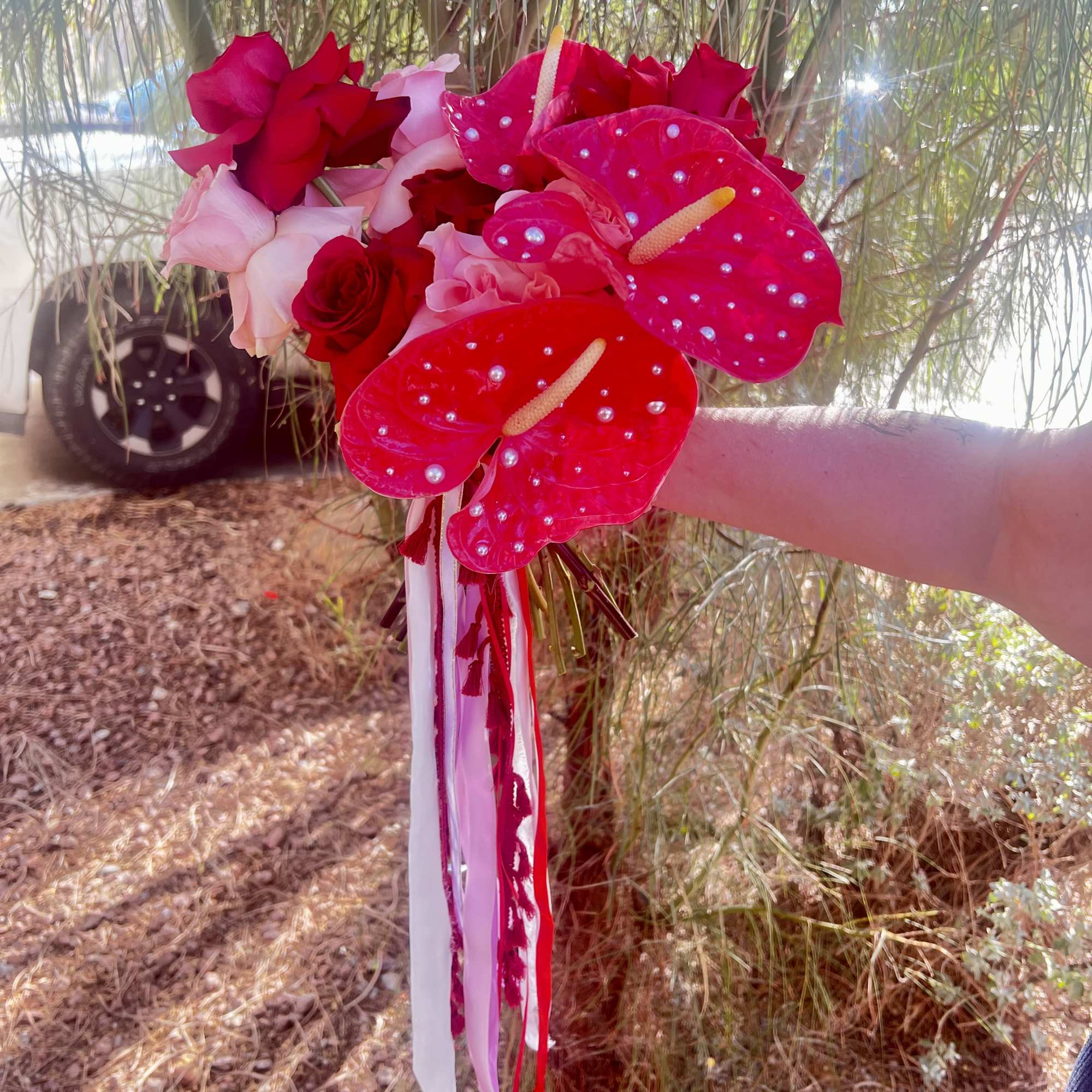 Handheld bouquet of red and pink roses with bright pink anthuriums