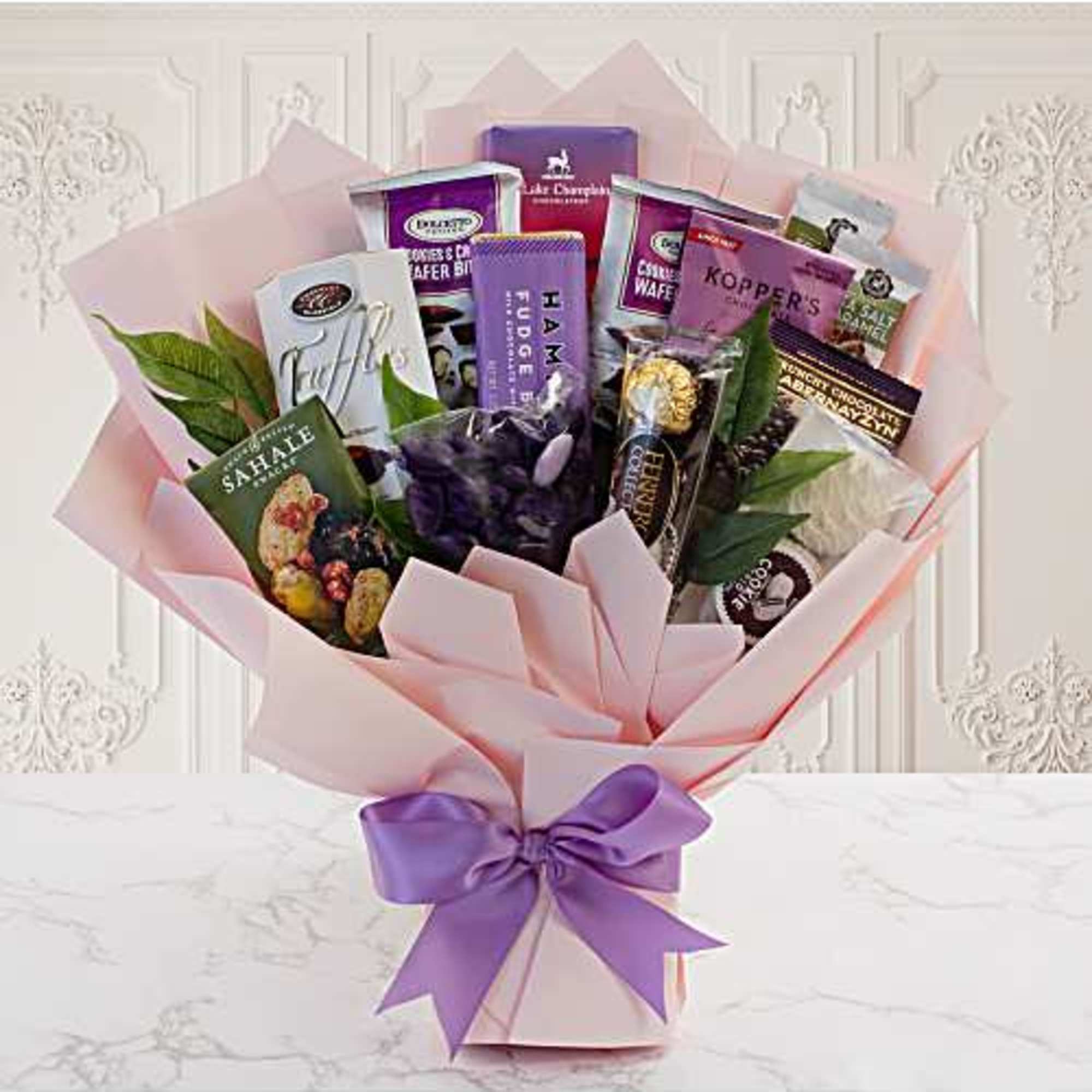 Gift bouquet of assorted chocolates wrapped in pink paper with a purple ribbon