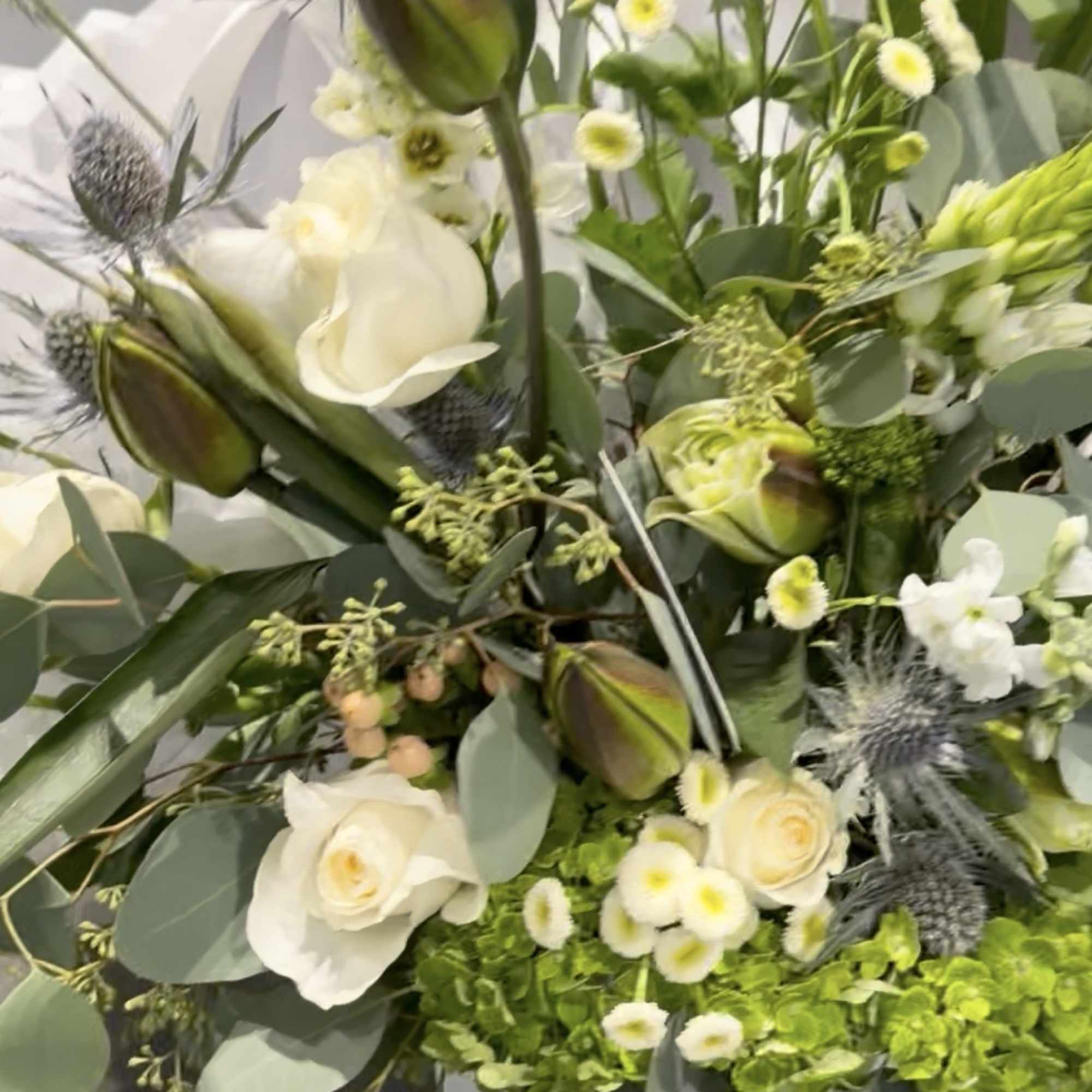 White floral bouquet with roses and mixed blooms in a black container