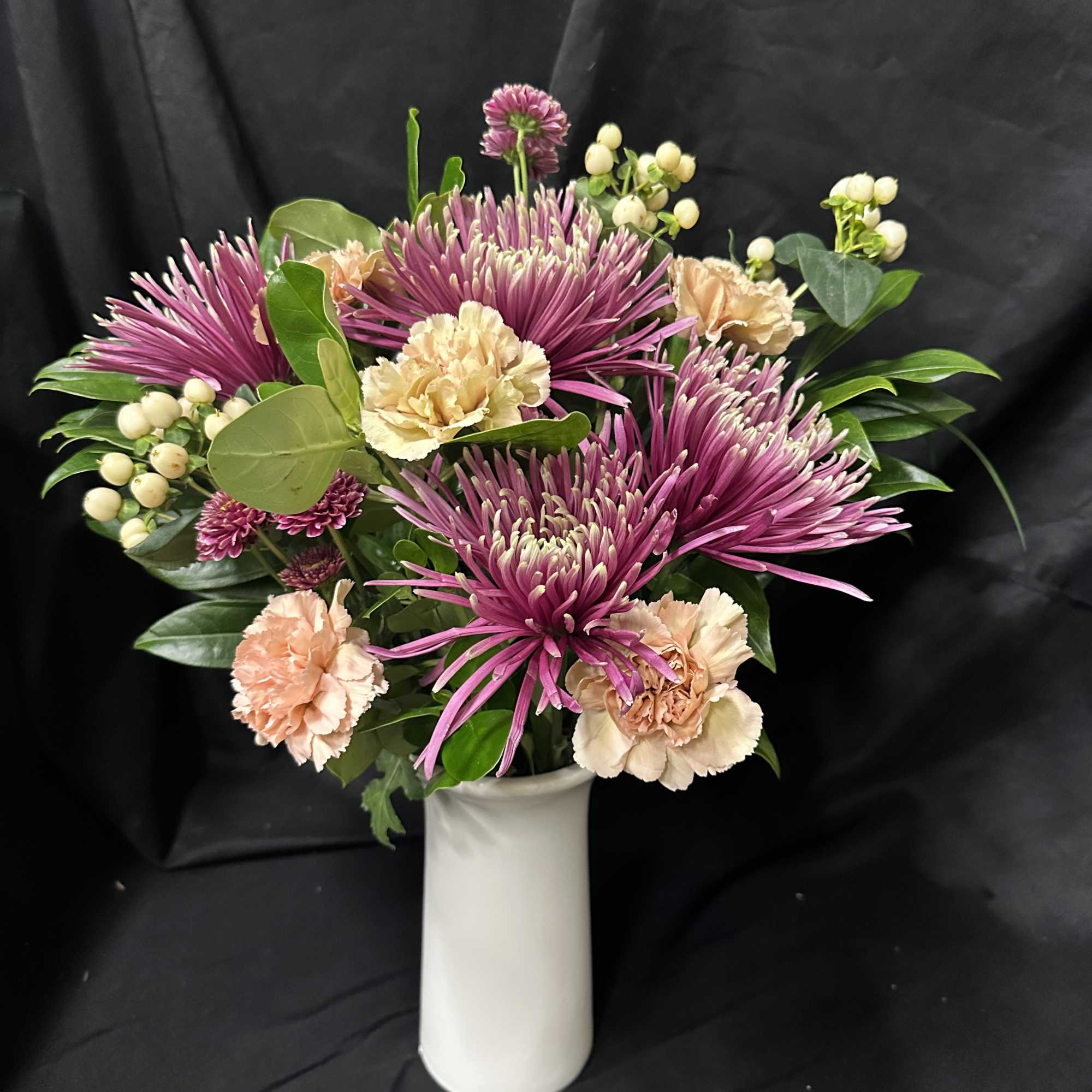 Pink chrysanthemums and peach carnations in a white vase