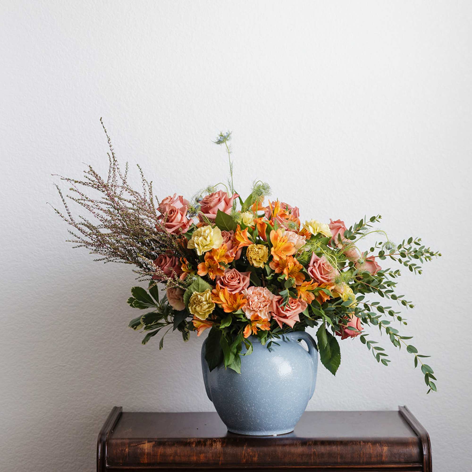 Mixed bouquet of pink and orange flowers in a blue vase