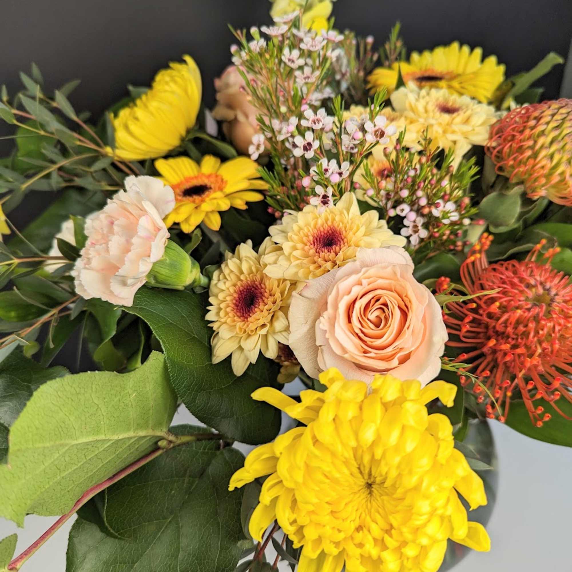 Bouquet of yellow and peach flowers with greenery