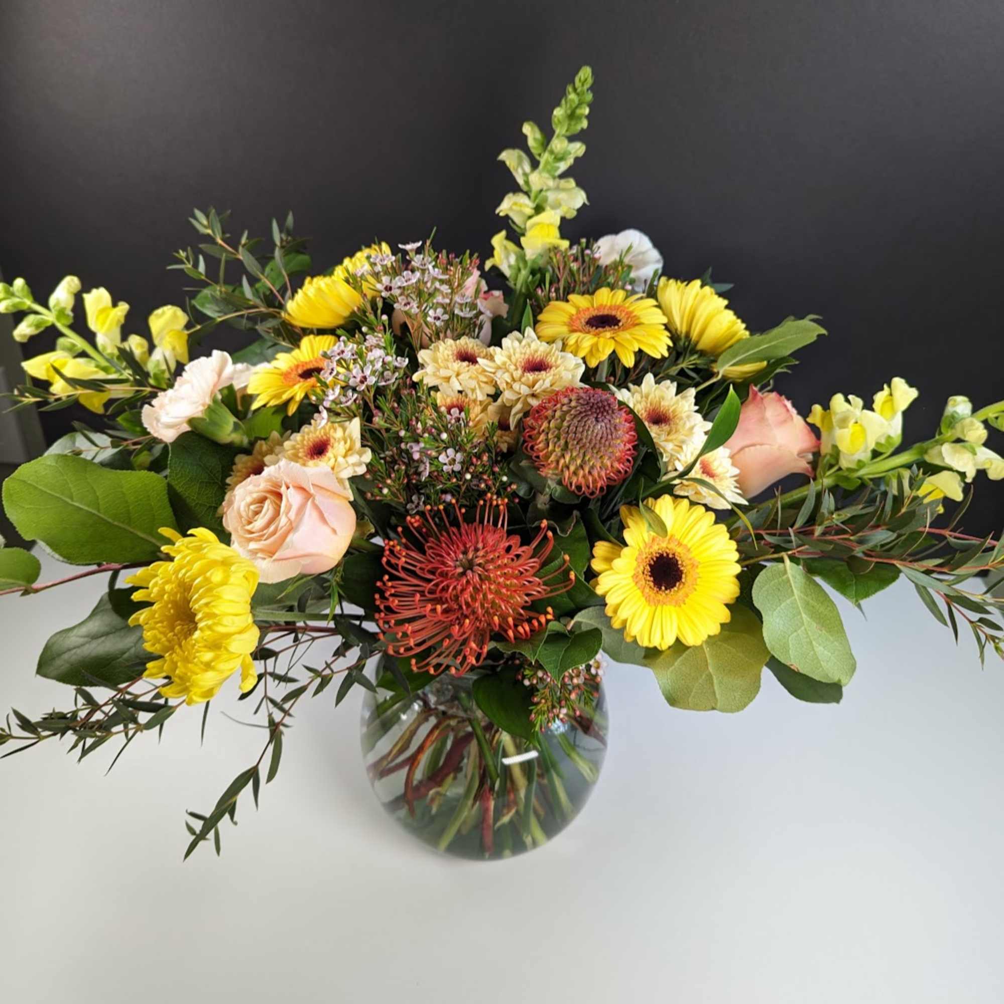 Mixed yellow and peach flowers in a glass vase