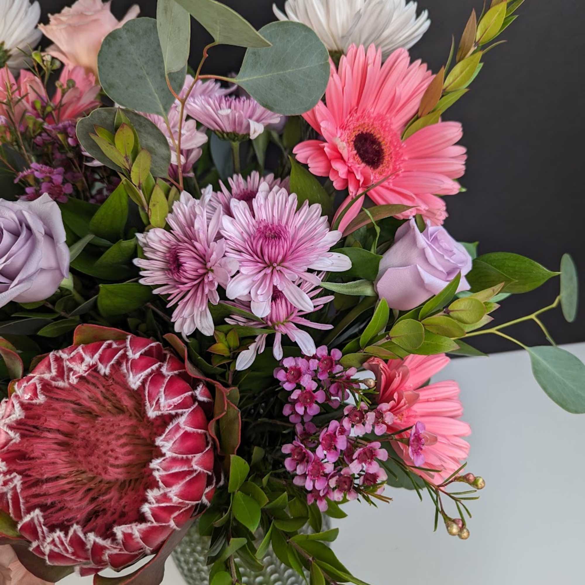 Bouquet with pink gerberas, lavender roses, and a protea