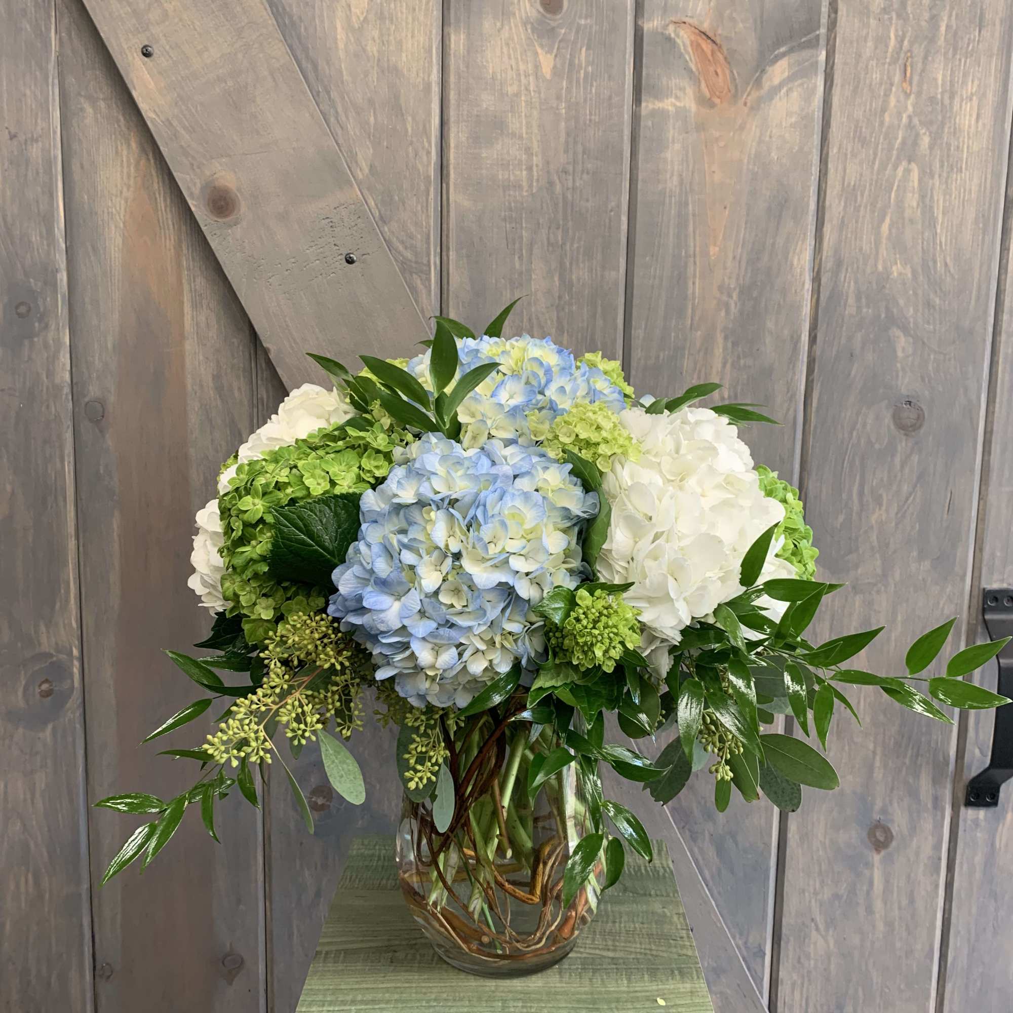 Blue and white hydrangea arrangement in a glass vase, photo 2 of 2