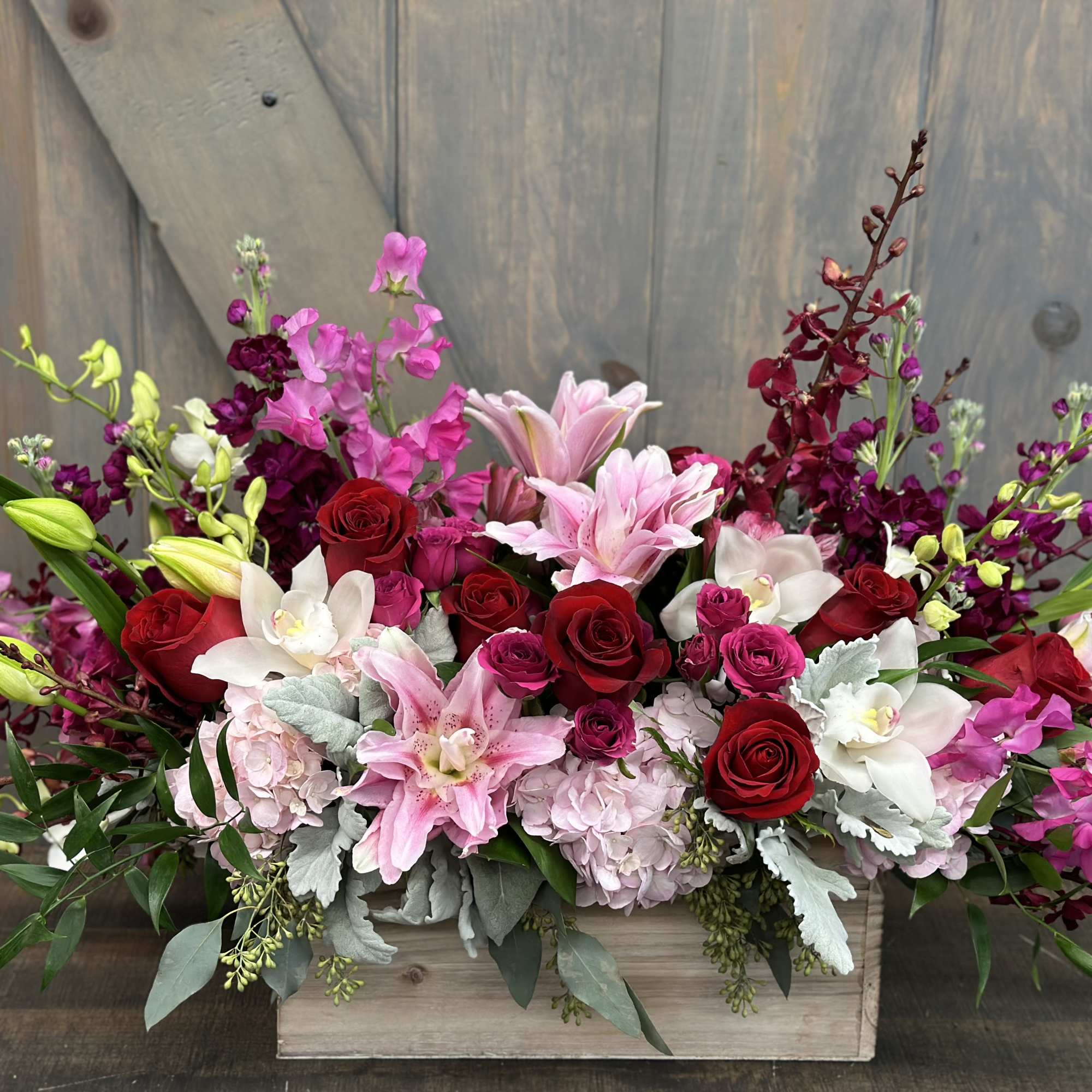Mixed bouquet of pink, red, and white flowers in a wooden box
