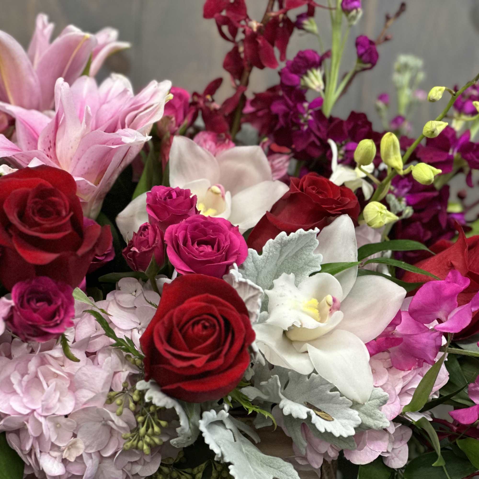 Bouquet of red roses, pink lilies, and white orchids