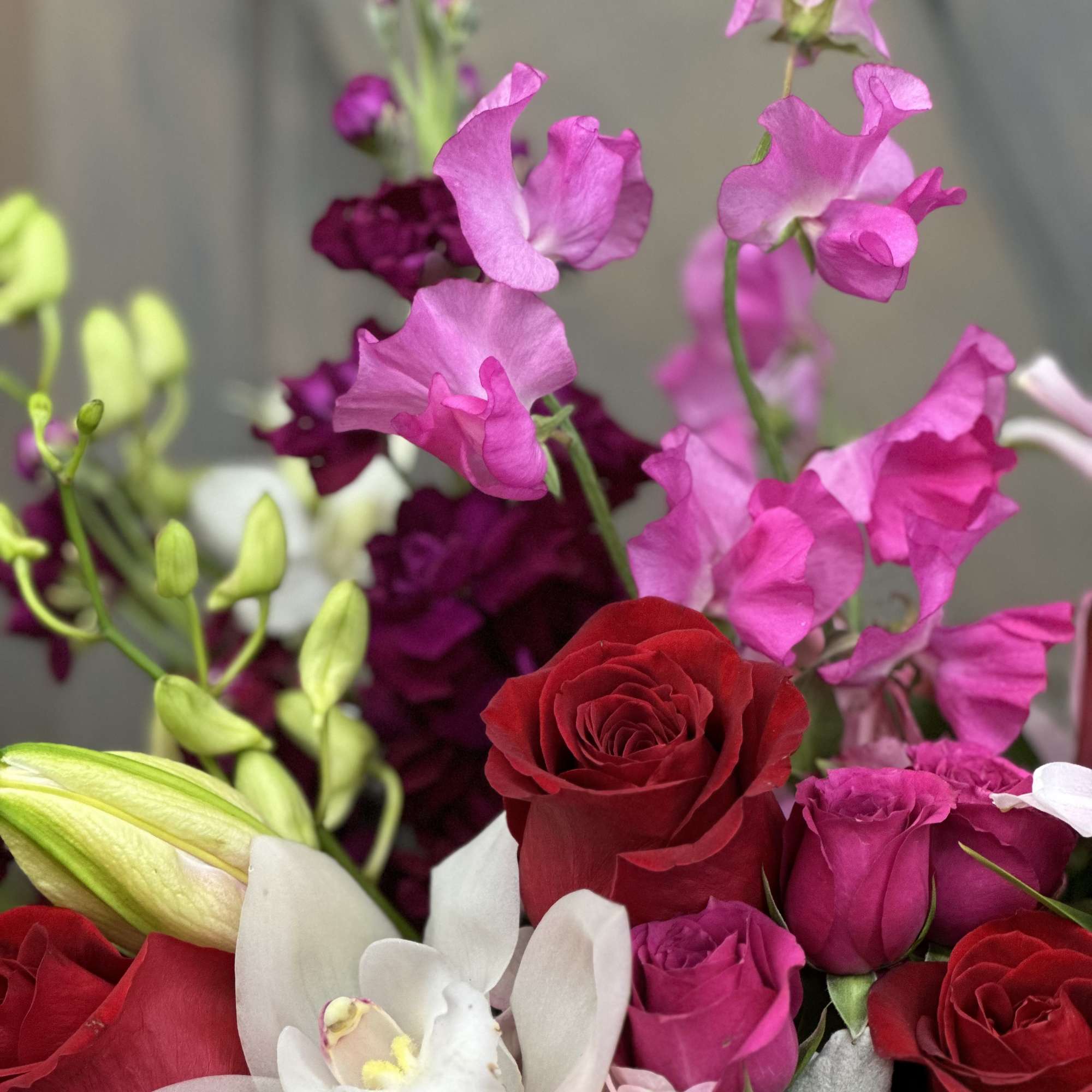 Bouquet of red roses, pink sweet peas, and white orchids