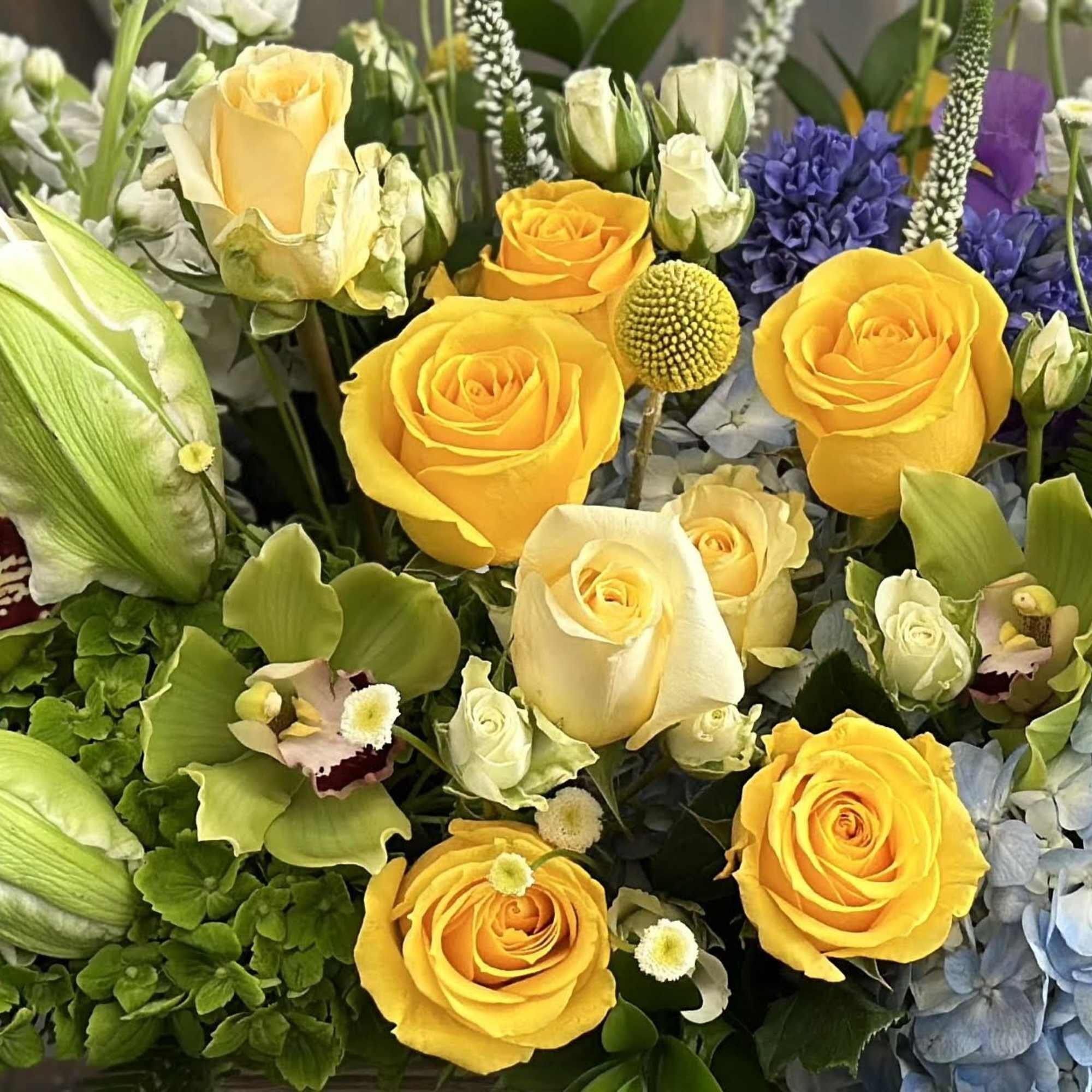 Bouquet of yellow roses, green orchids, and blue hydrangeas
