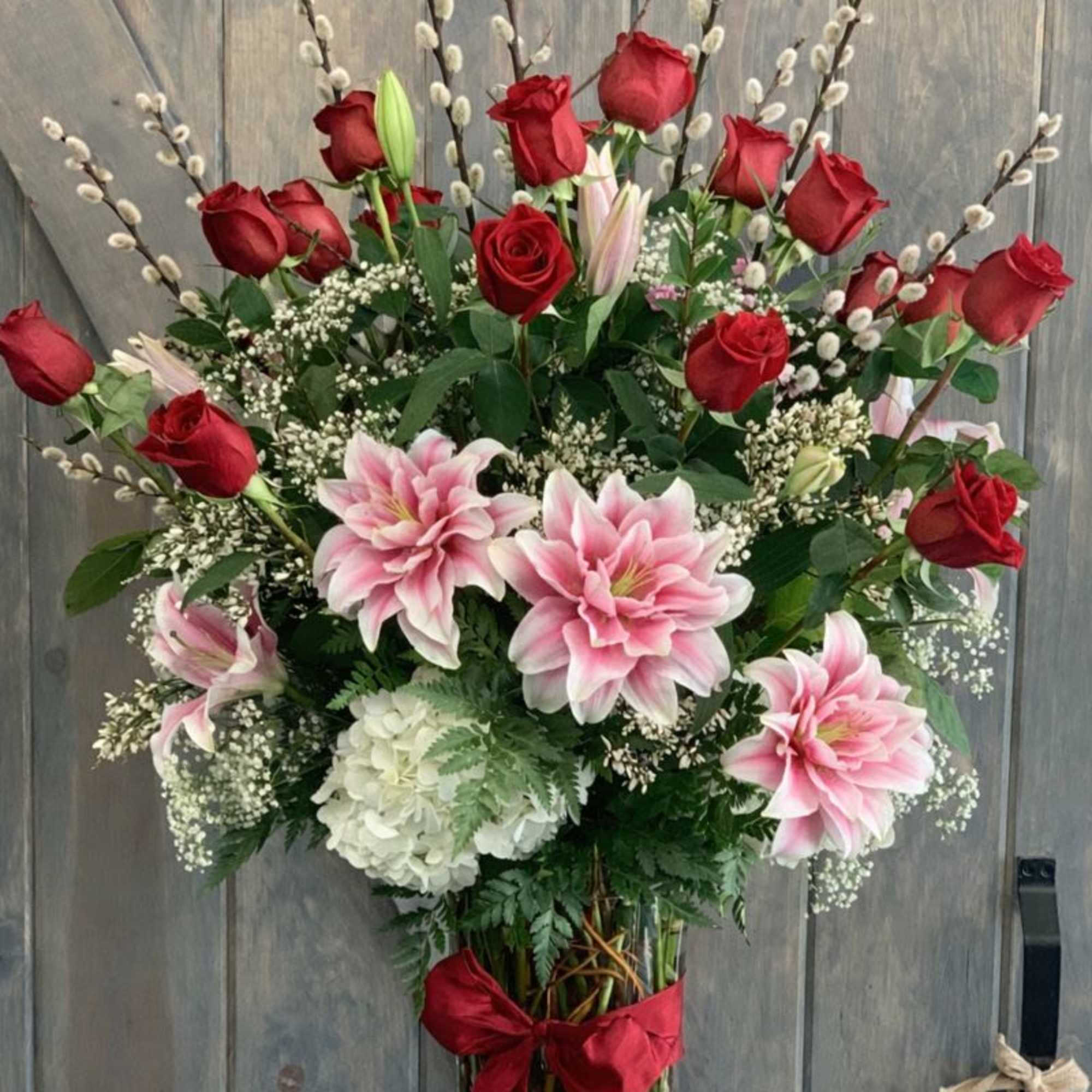 Tall bouquet of red roses and pink lilies in a glass vase